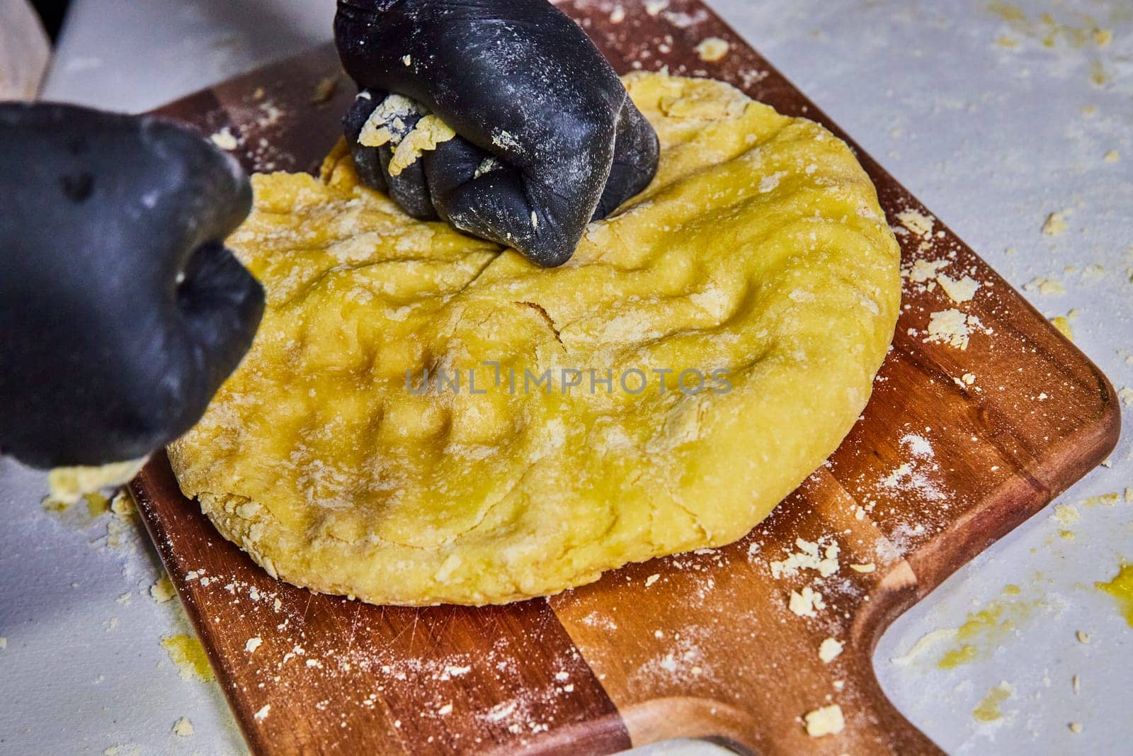 Professional hands kneading pasta dough in a warm, hygienic setting in Fort Wayne, Indiana - a perfect snapshot of culinary precision and safety.