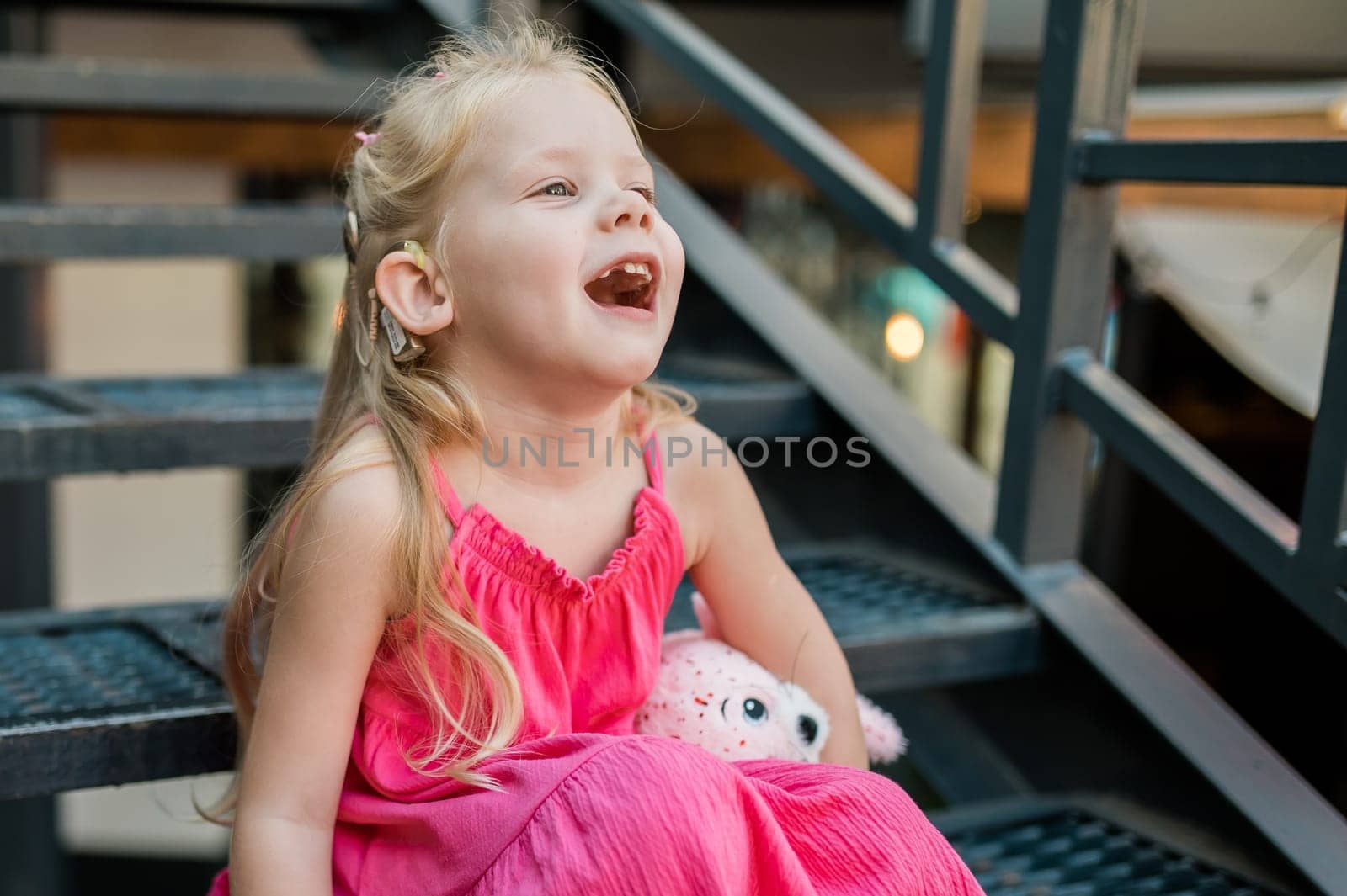 Child girl with hearing aids and cochlear implants having fun outdoor speak and playing. Copy space and empty place for advertising. Inclusion by Satura86