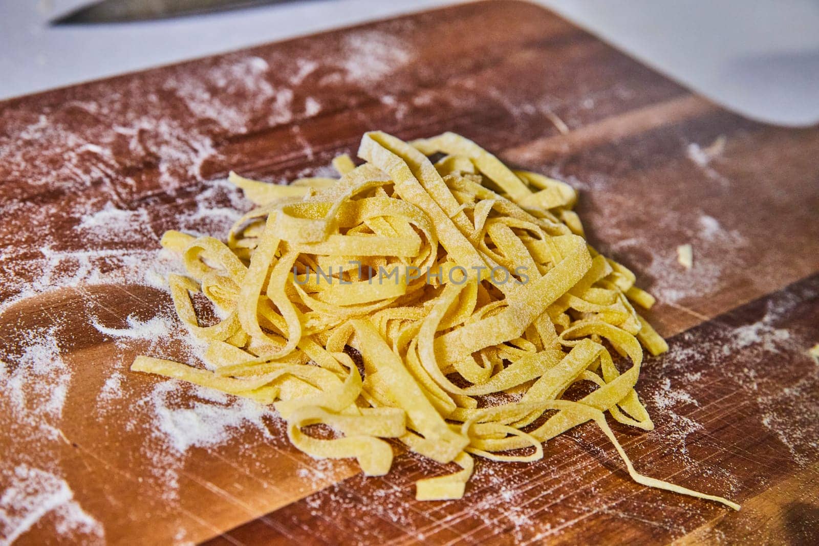 Handcrafted fettuccine pasta on a rustic wooden board in a sunlit kitchen, showcasing traditional Italian culinary art from Indiana.