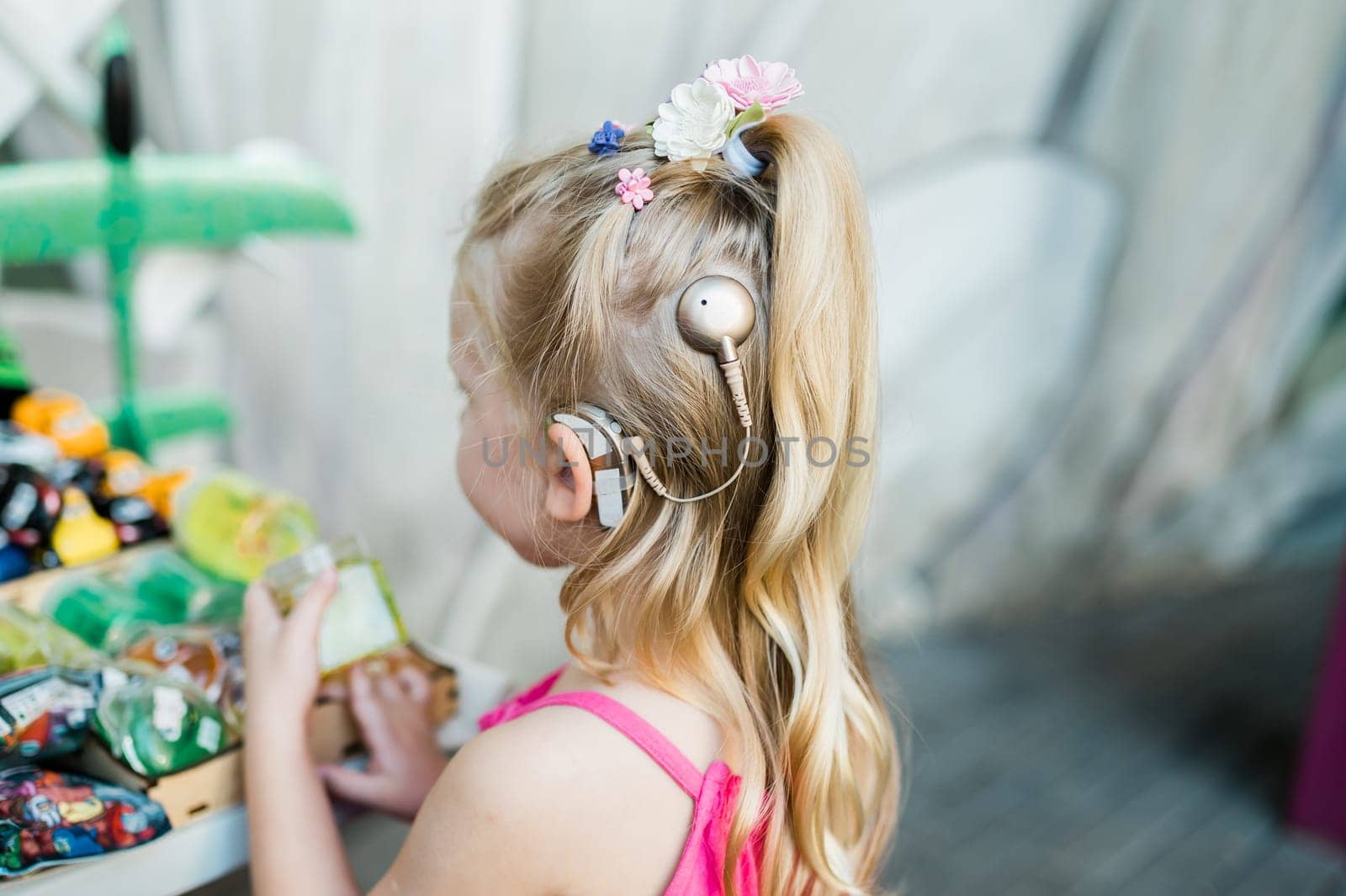 Child walks with cochlear implant hearing aid in summer street. Inclusion and modern technologies for treating hearing loss.