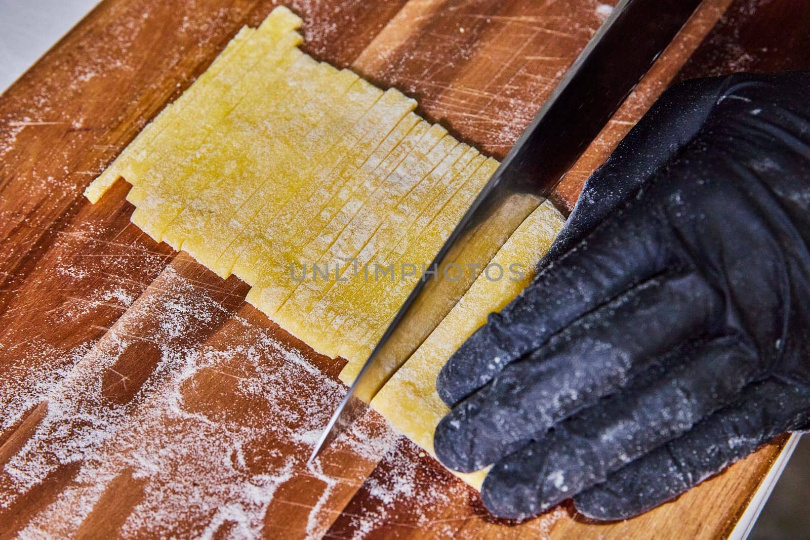Artisanal Pasta Preparation in Fort Wayne - Hand Cutting Fresh Tagliolini Dough on a Rustic Wooden Board