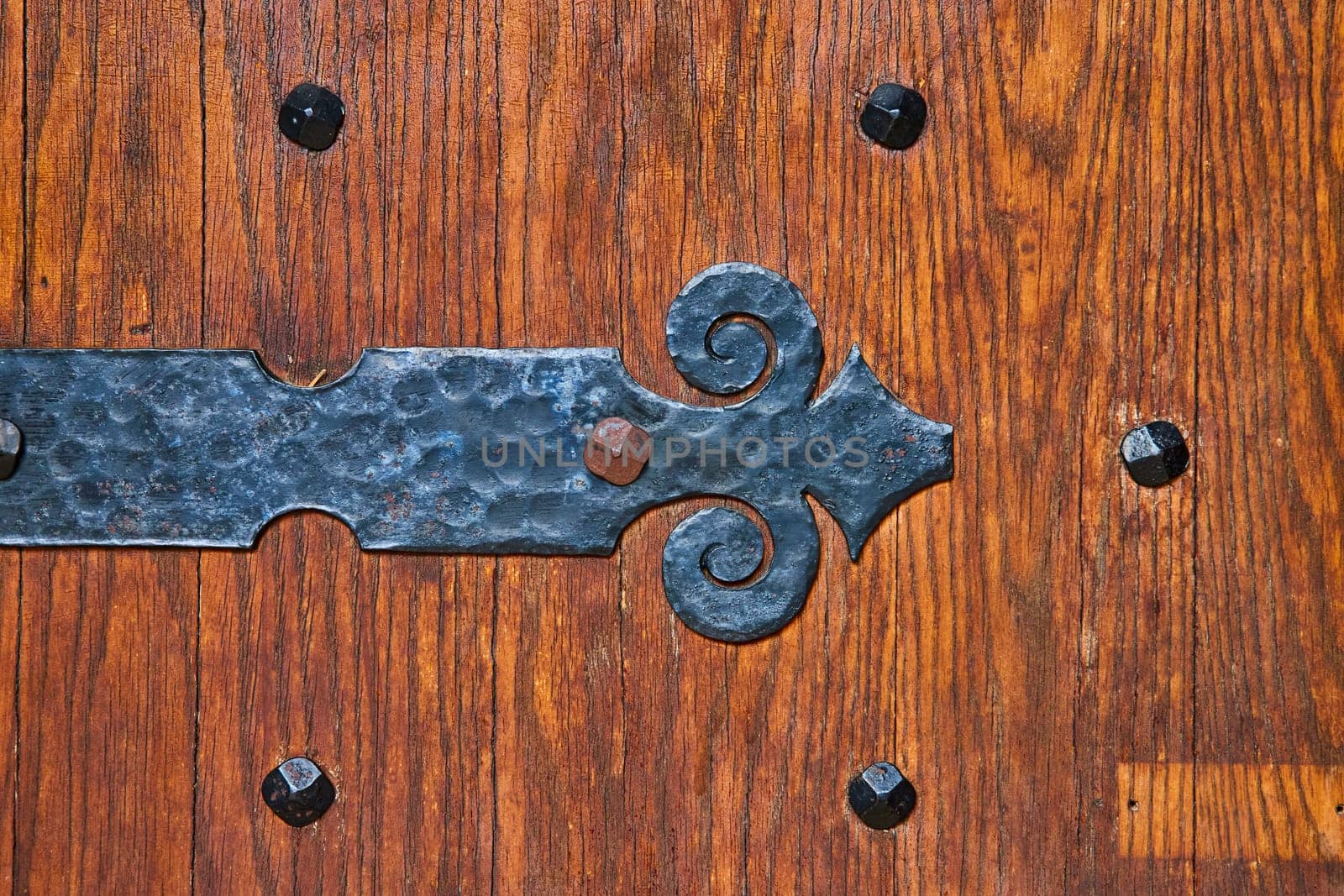 Artisanal wrought iron hinge on an antique wooden door at Bishop Simon Brute College, symbolizing timeless craftsmanship.