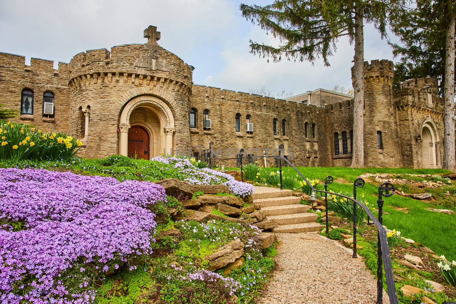 Springtime at Bishop Simon Brute College, Indiana - Historic castle with intricate Christian details amid vibrant gardens.