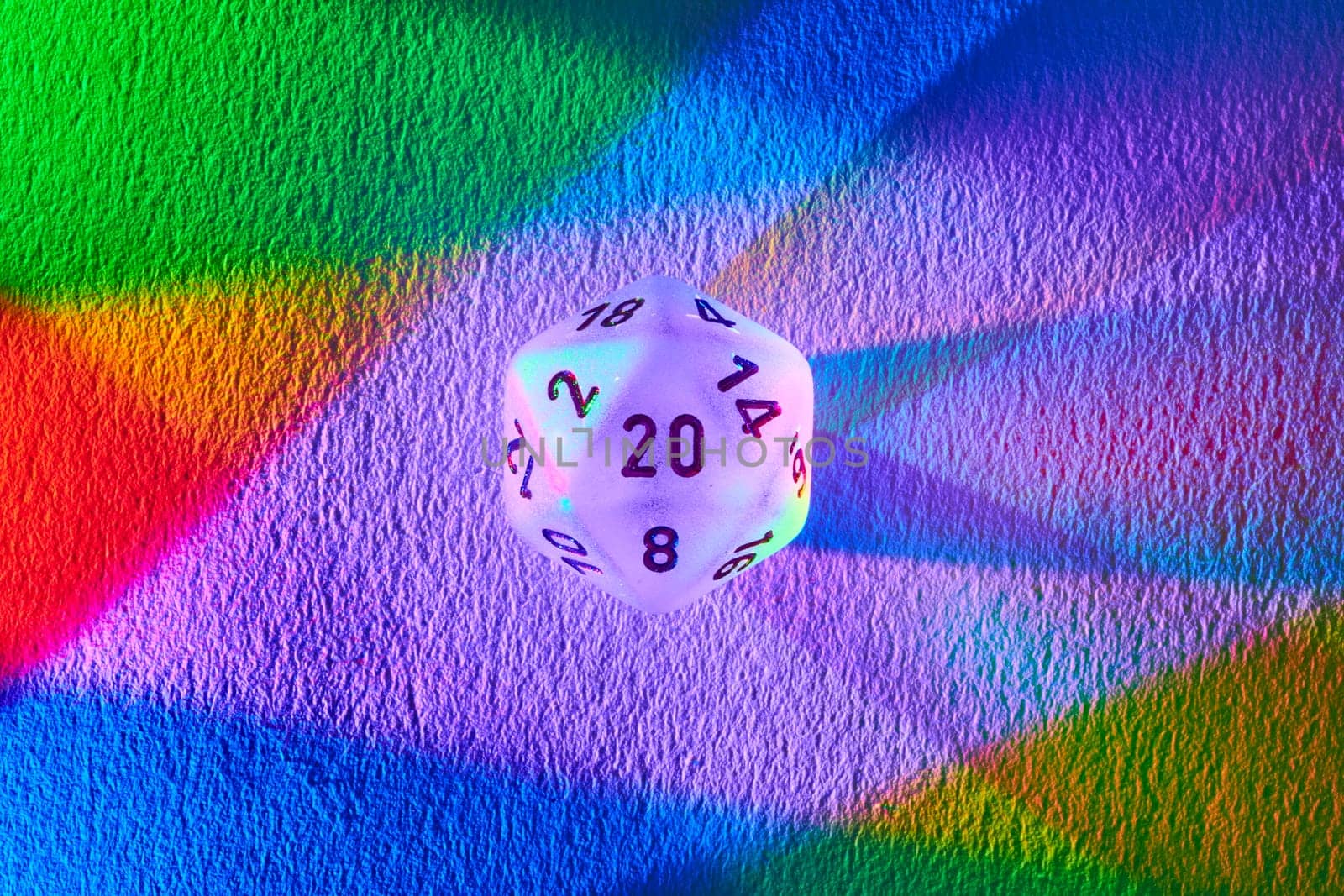 Vibrant 20-sided dice casting a rainbow spectrum on textured surface, symbolizing diversity, chance, and strategy in Fort Wayne, Indiana.