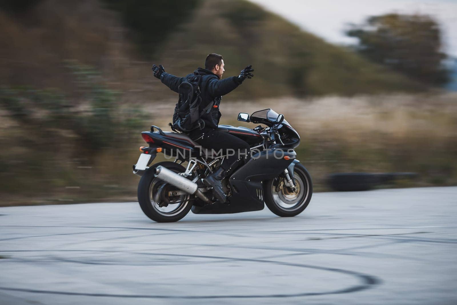 Young biker riding a sport motorbike without hands and feel free. Freedom concept. Motion blur on background.