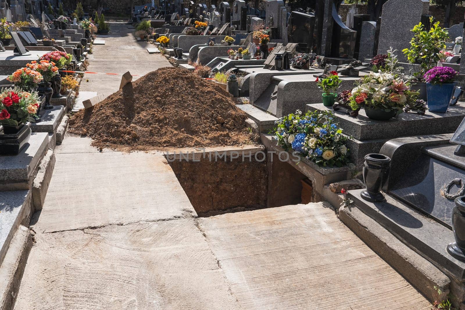 A freshly dug grave in the cemetery. Funeral preparation. Open grave in graveyard. by Godi