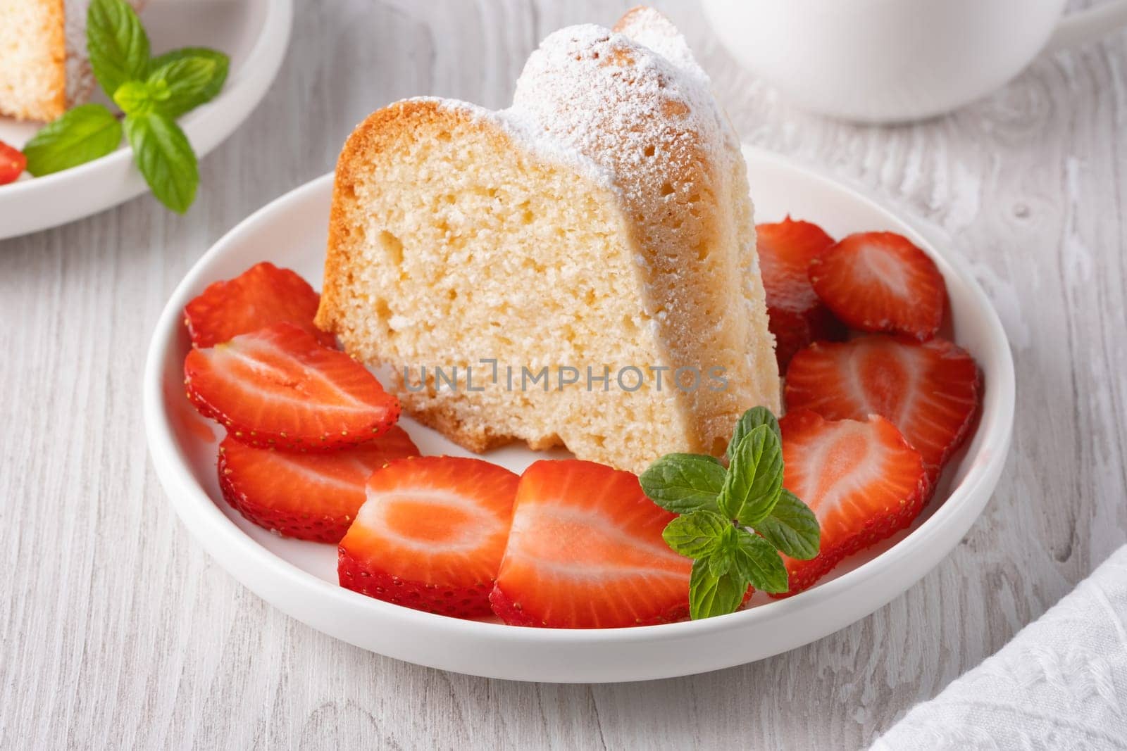 Piece of cupcake with strawberries on a plate.