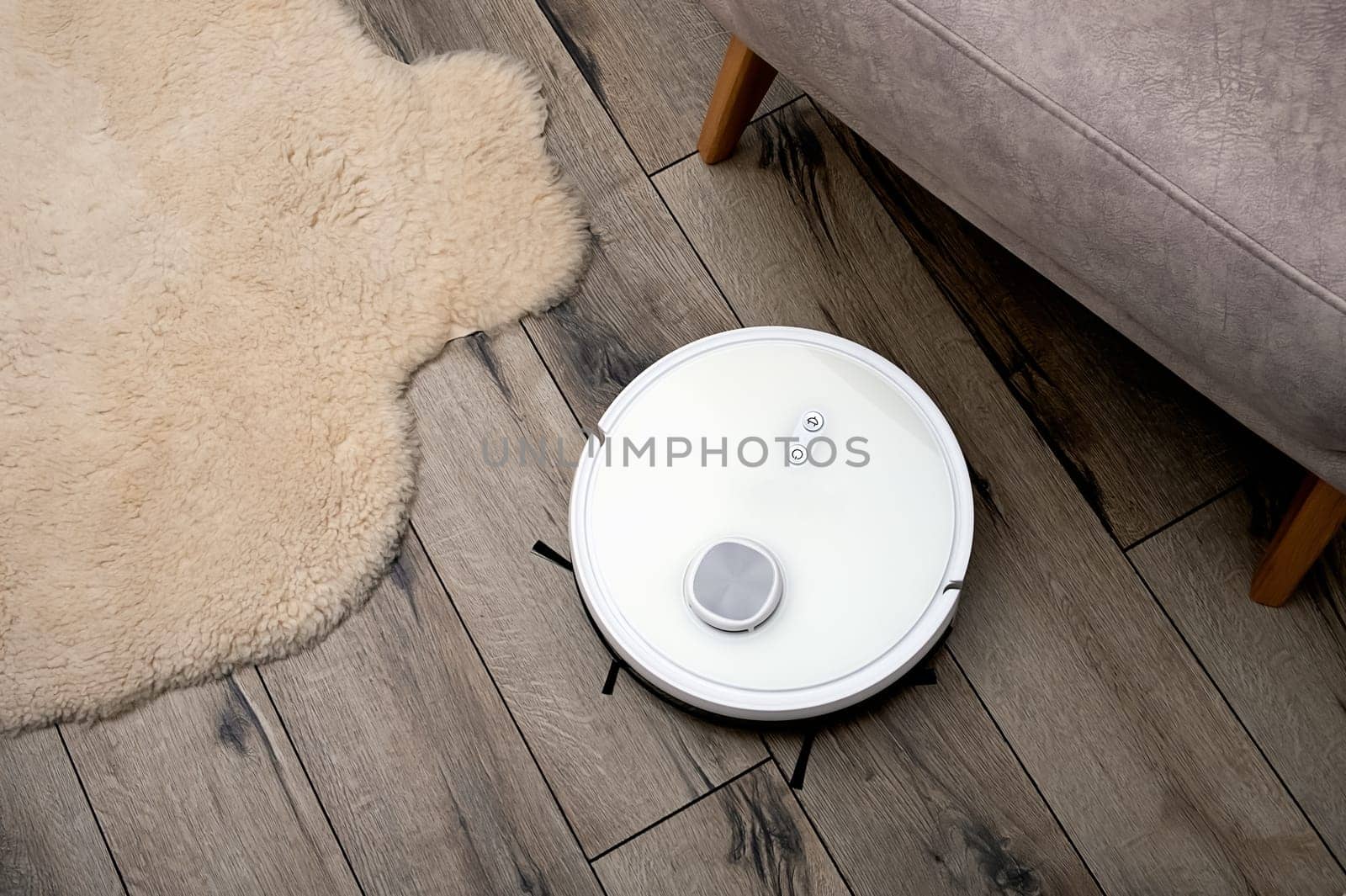 A robot vacuum cleaner on a wooden floor. Technologies for home cleaning. Selective focus.