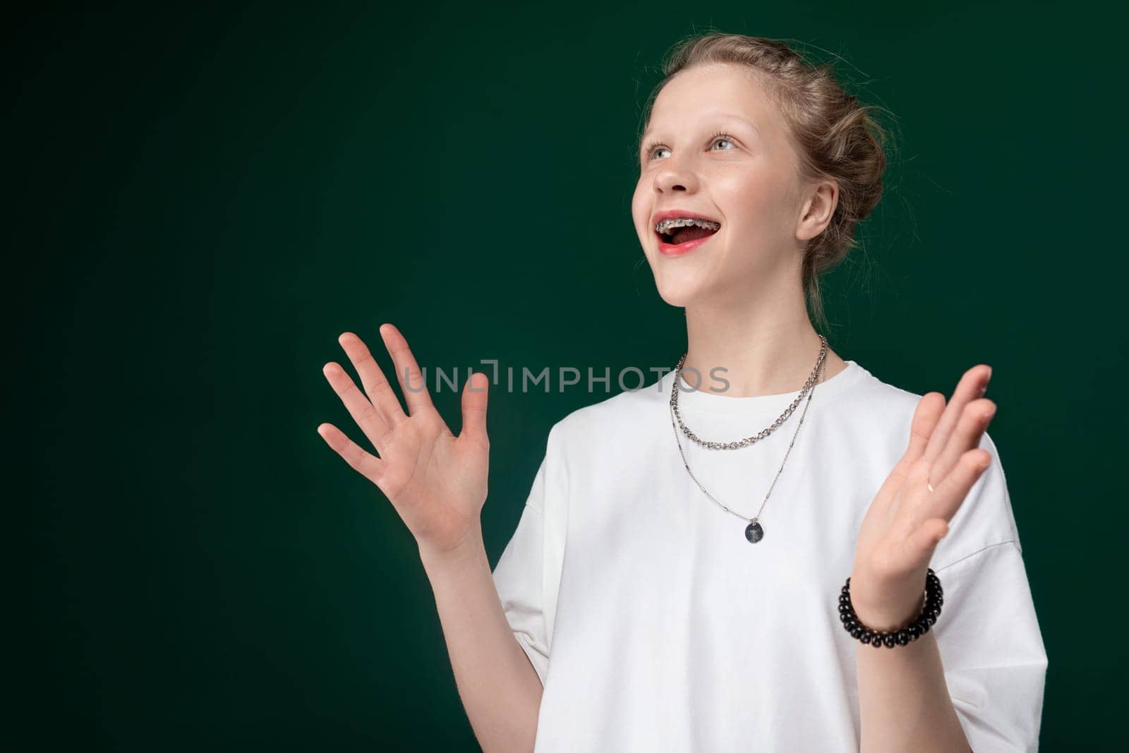 A Caucasian woman wearing a white shirt is standing with her arms extended outwards in a gesture of openness or surrender.