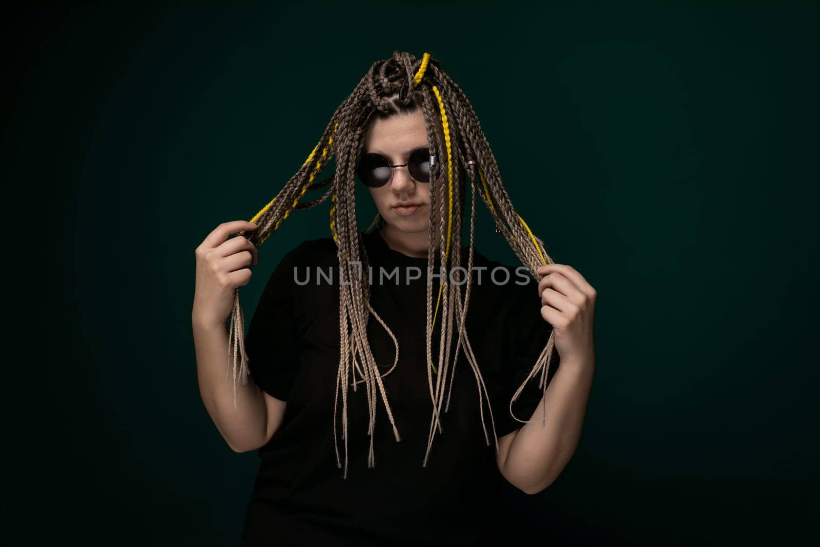 A man with dreadlocks is holding his long hair in front of his face, covering his features. His hair is styled in thick, twisted strands that reach down to his chest. The mans face is partially obscured by the curtain of hair, creating a mysterious and introspective atmosphere.