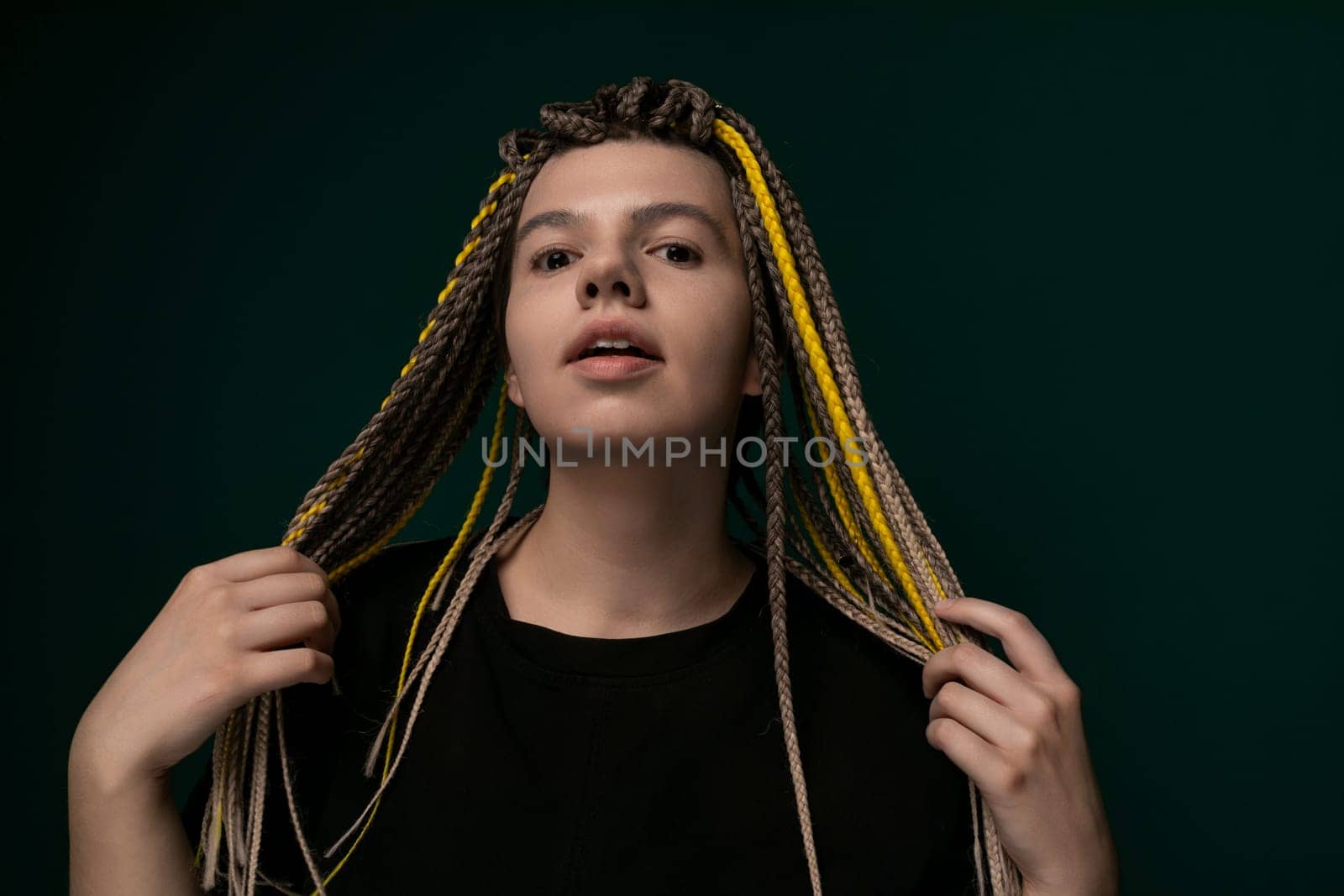 A woman with dreadlocks is standing upright in front of a vivid green background. Her hair is styled in long, thick dreadlocks that cascade down her back. She is looking confidently at the camera, exuding a sense of strength and individuality.