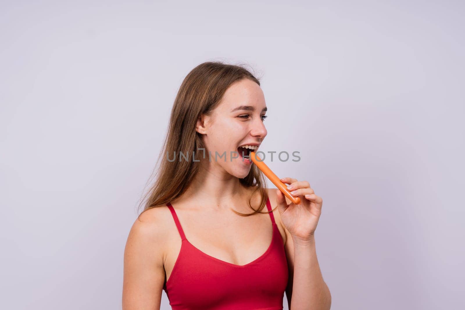 Close-up of a woman eating a sausage. Cropped photo in studio by Zelenin