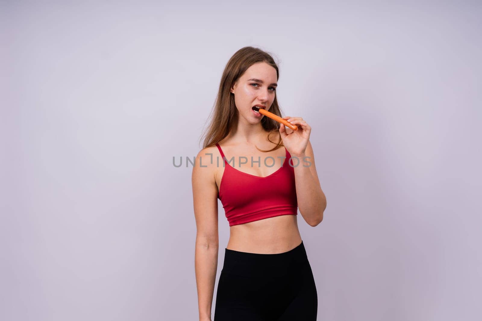 Close-up of a woman eating a sausage. Cropped photo in studio by Zelenin