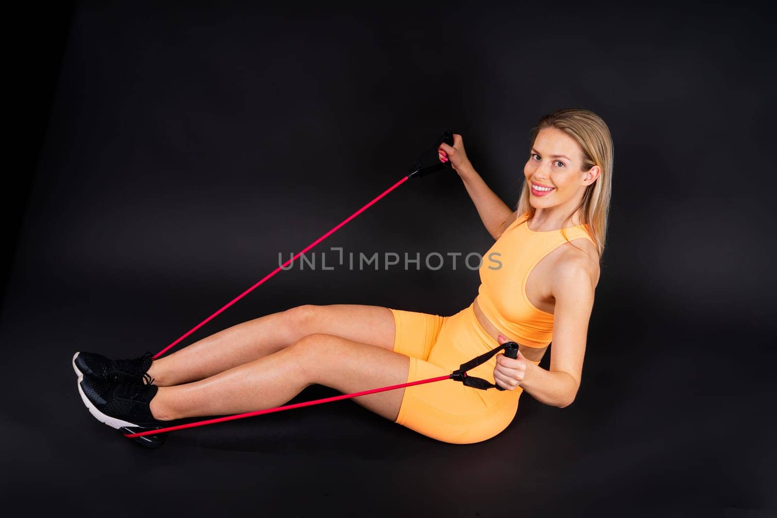 Sportswoman performs exercises for the muscles of a chest. Workout with resistance band.