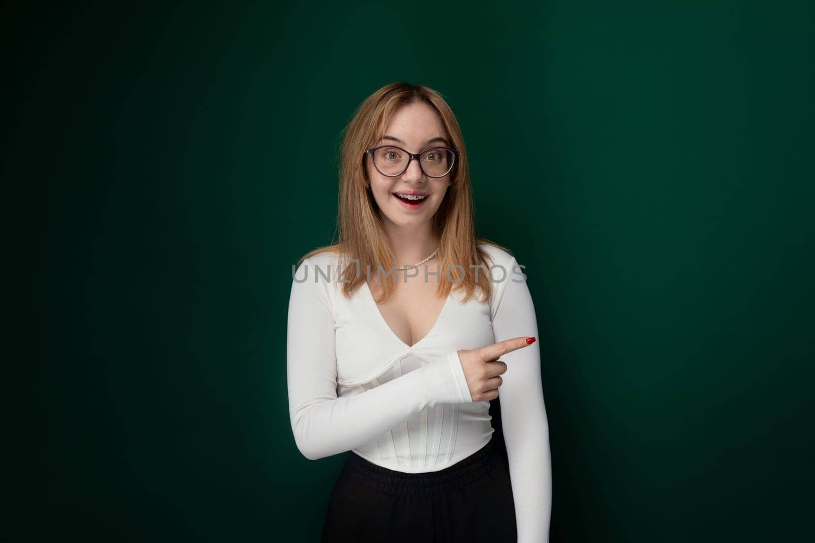 A woman with glasses is seen pointing at an object or direction, indicating interest or importance. She is wearing a casual outfit and appears focused on the target of her gesture.