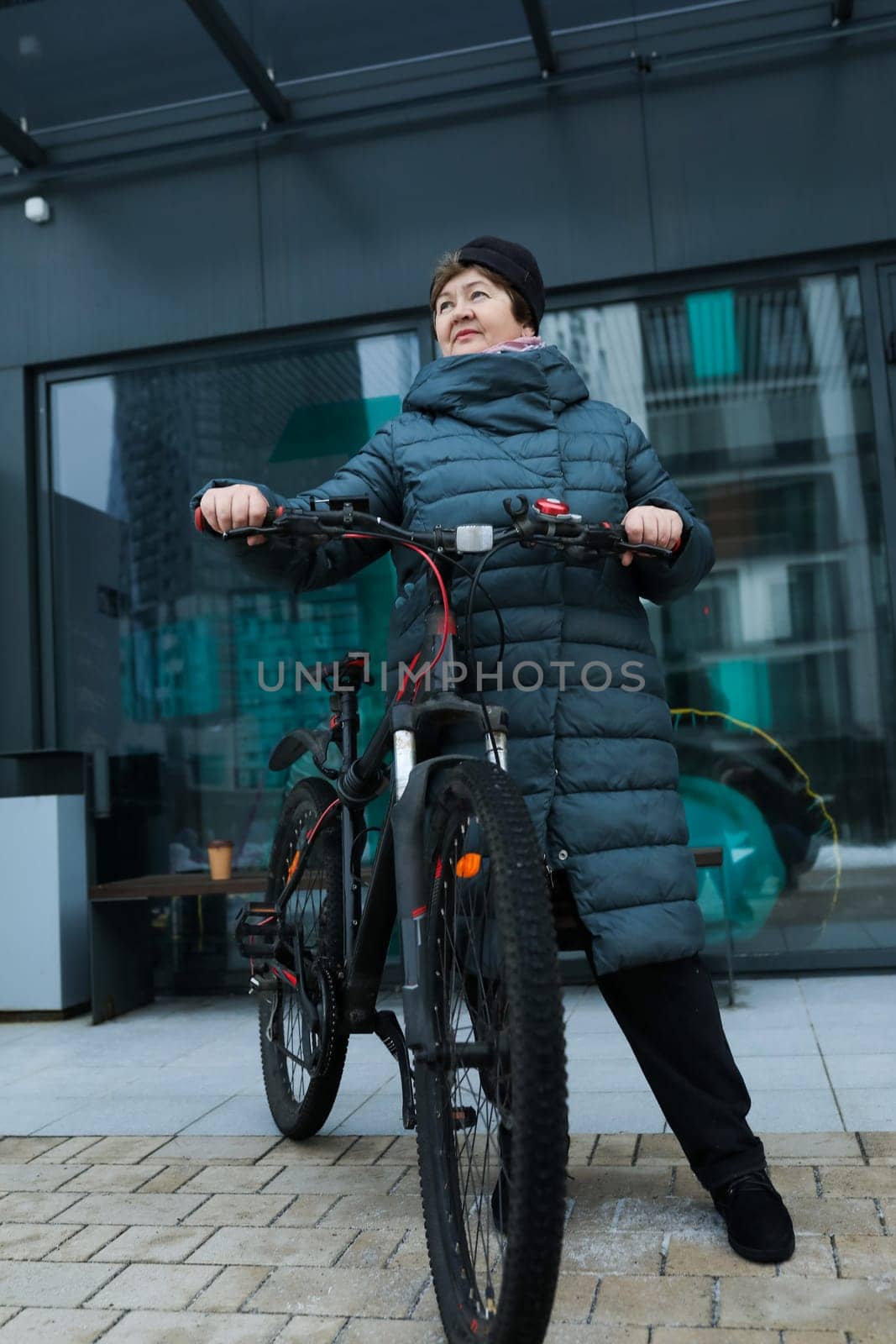 Elderly woman doing sports and riding a bicycle on the street.