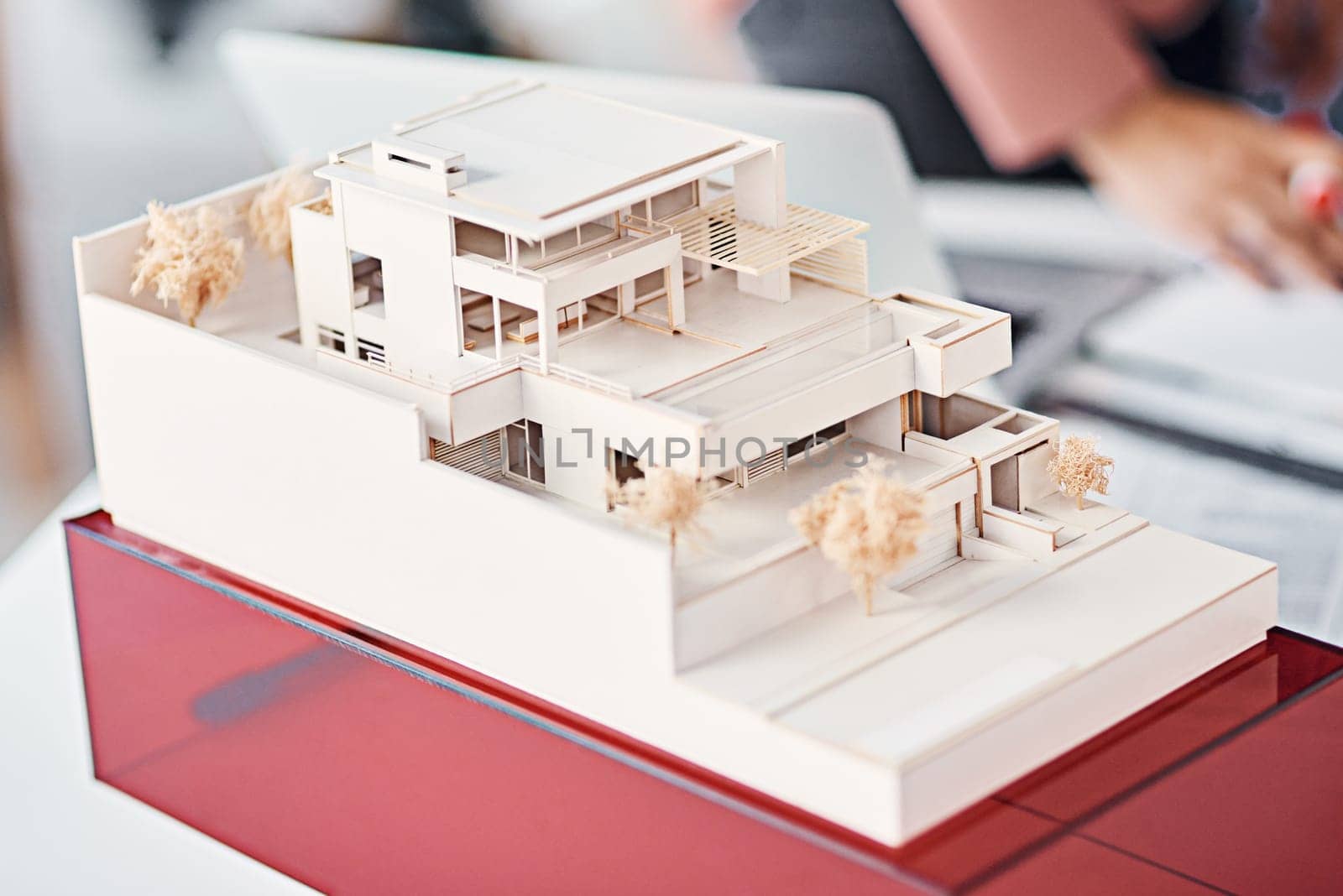 Architecture, closeup and model of modern house on desk with people, planning and vision for real estate. Design, engineering and development for property agency, expansion and presentation at office.