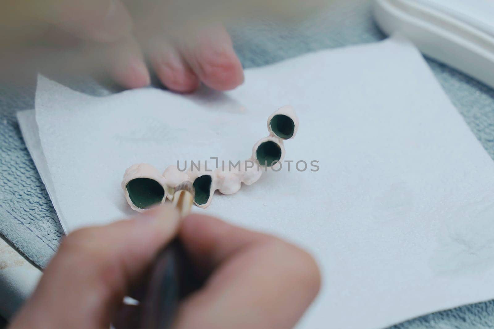 Dental Technician Working With Ceramic Crowns In Dental Laboratory. Close-up
