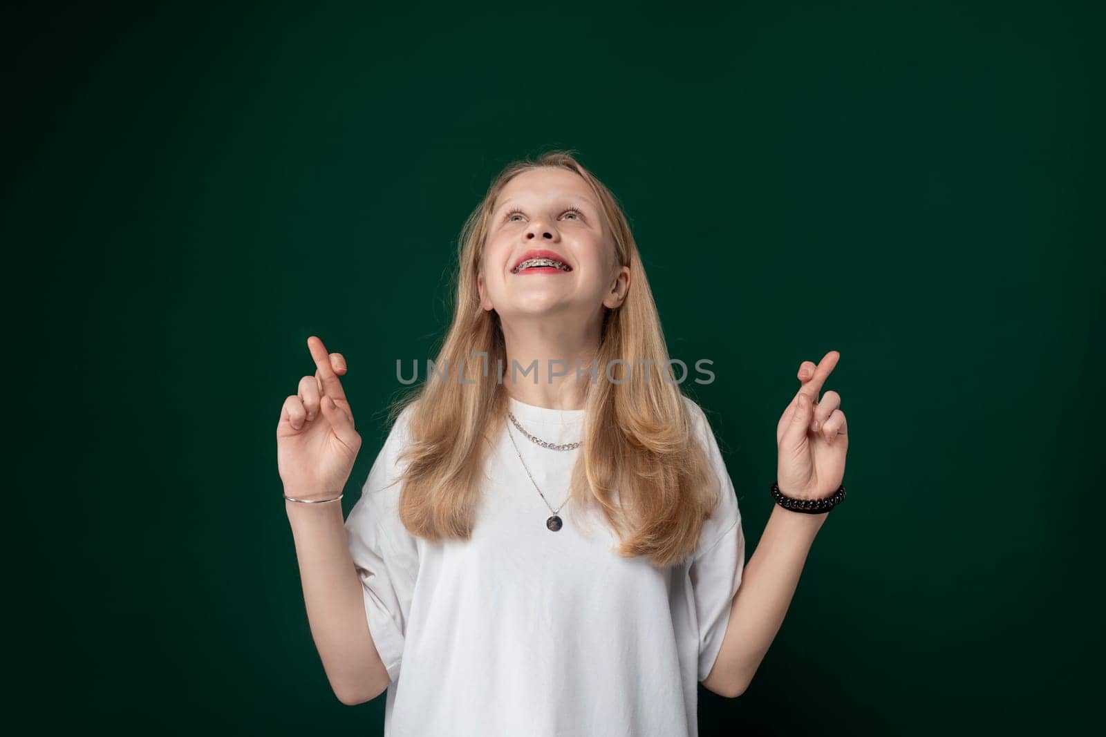 A woman standing upright in front of a green wall, looking directly at the camera. She appears calm and composed in her posture.