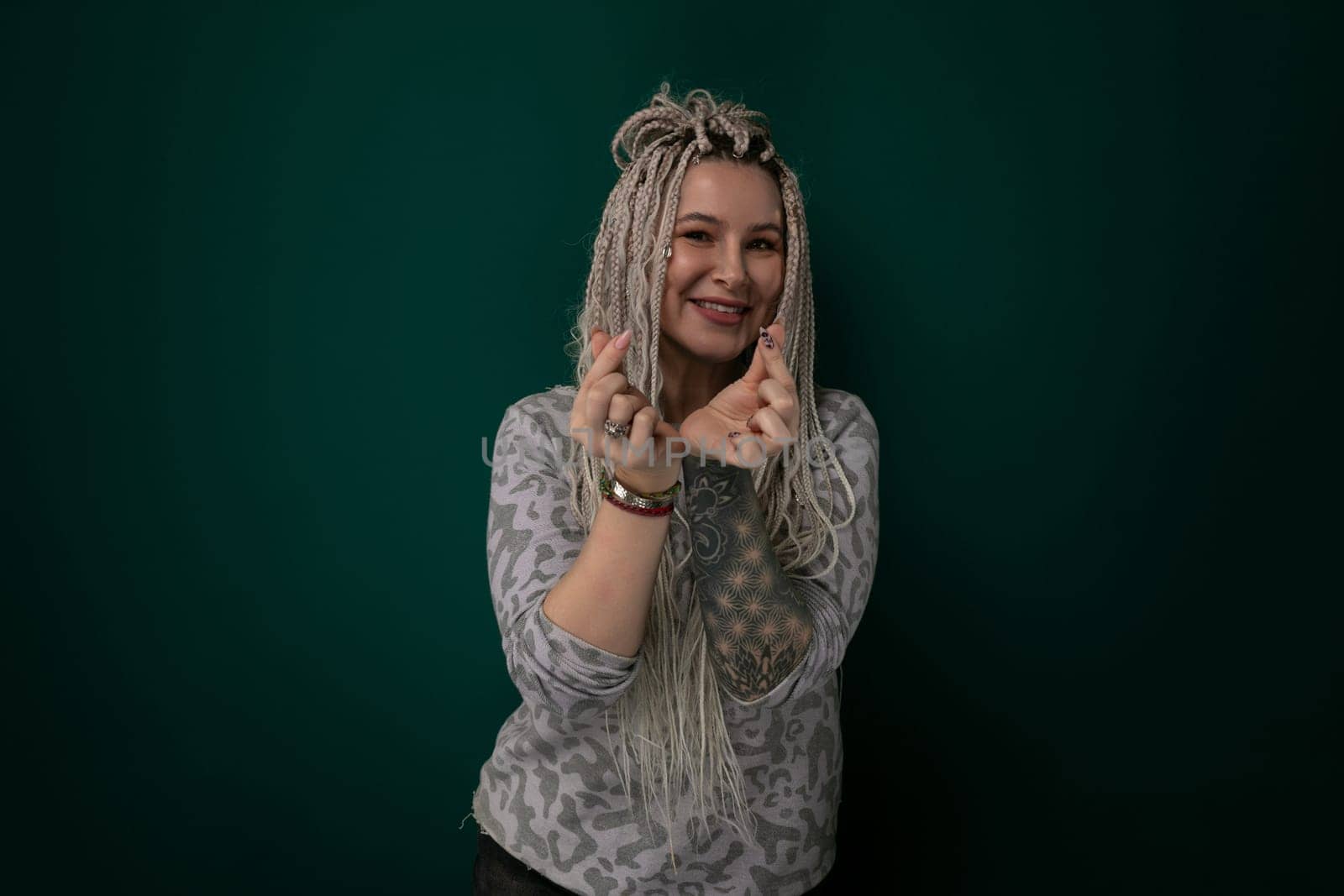 A woman with dreadlocks standing confidently in front of a vibrant green background. She exudes a sense of strength and individuality through her unique hairstyle and posture.