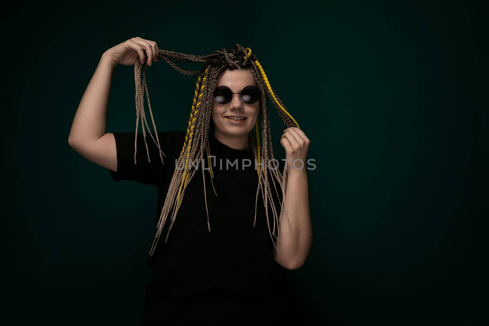 A woman with long dreadlocks on her head is striking a pose while someone takes her photo. She is looking directly at the camera with a confident expression, showcasing her unique hairstyle.