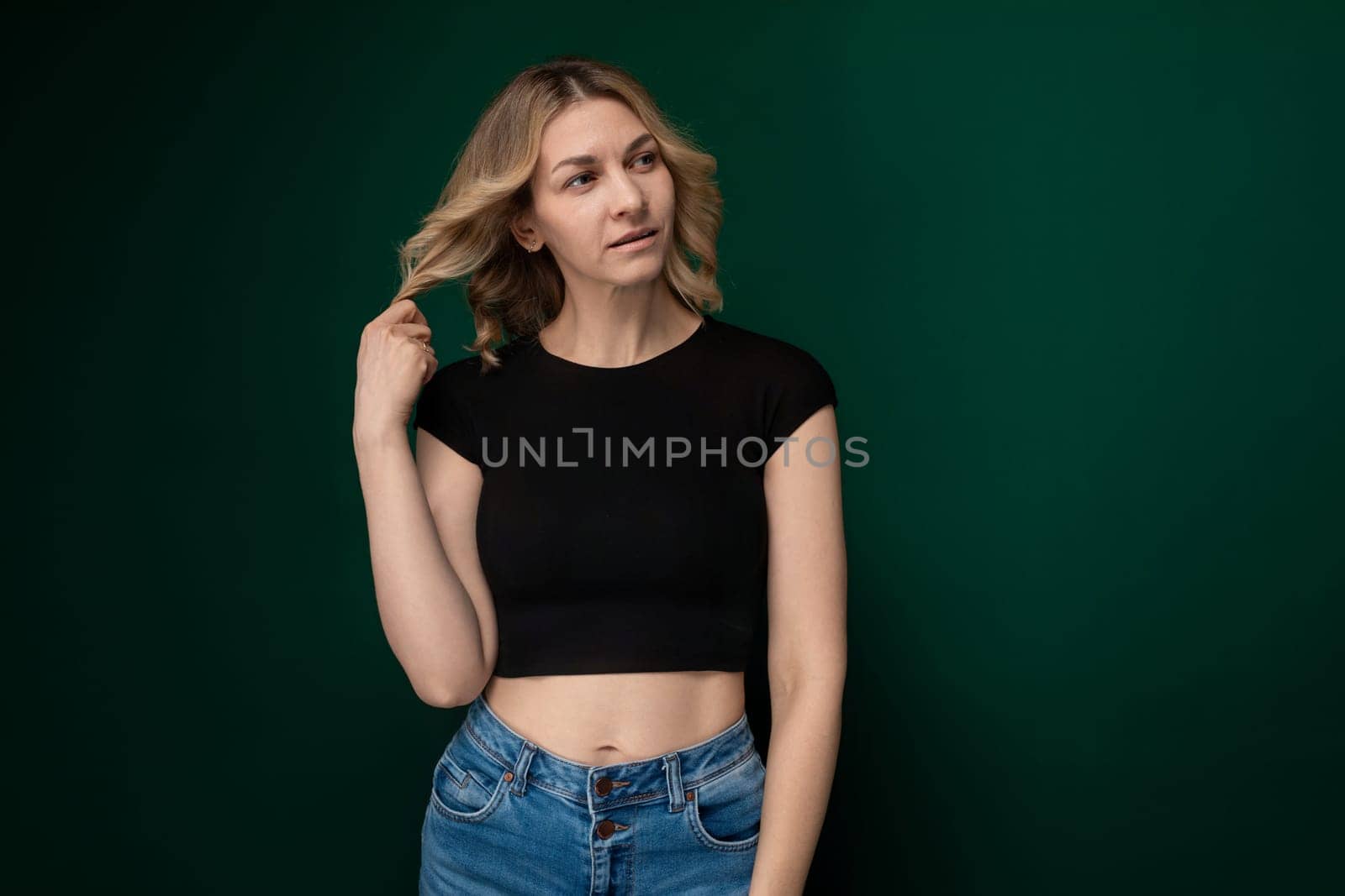 A young woman wearing a black crop top strikes a pose for a photograph, showcasing confidence and style. Her body language exudes self-assuredness as she flaunts her outfit.