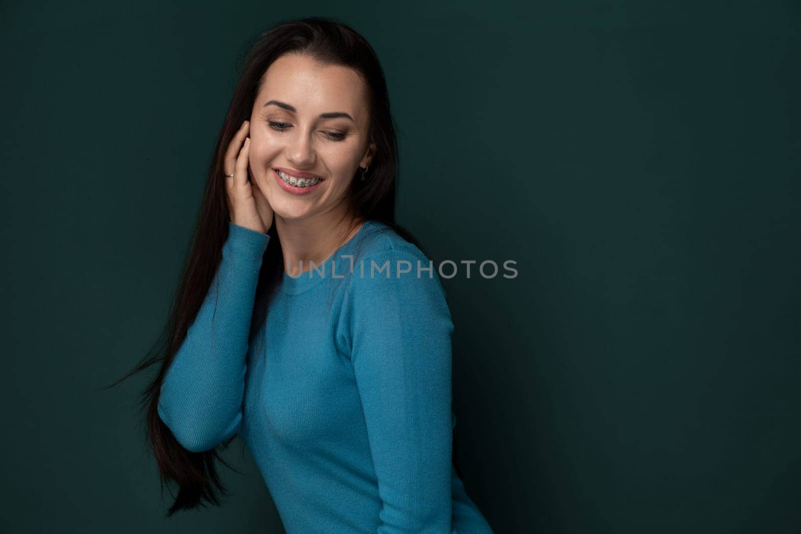 Smiling Woman in Blue Shirt Leaning Against Green Wall by TRMK