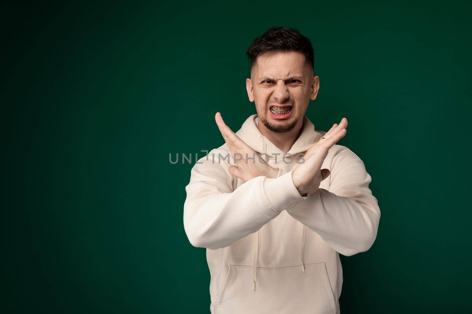 A man is using his hands to make a gesture. He is standing in a bright room with white walls. The man appears focused on his hand movements, expressing something non-verbally.