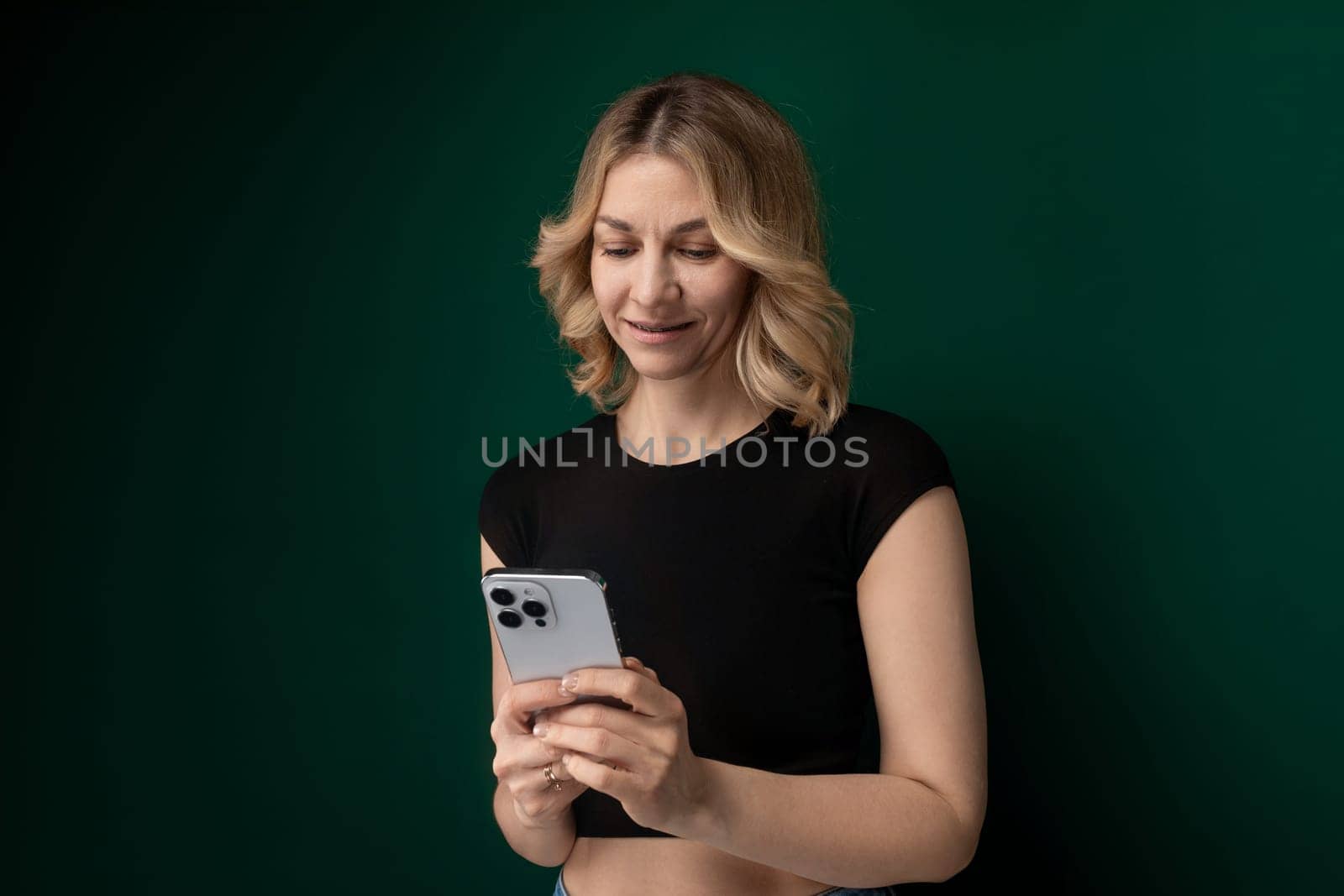 A woman wearing a black shirt is holding a cell phone in her hand.