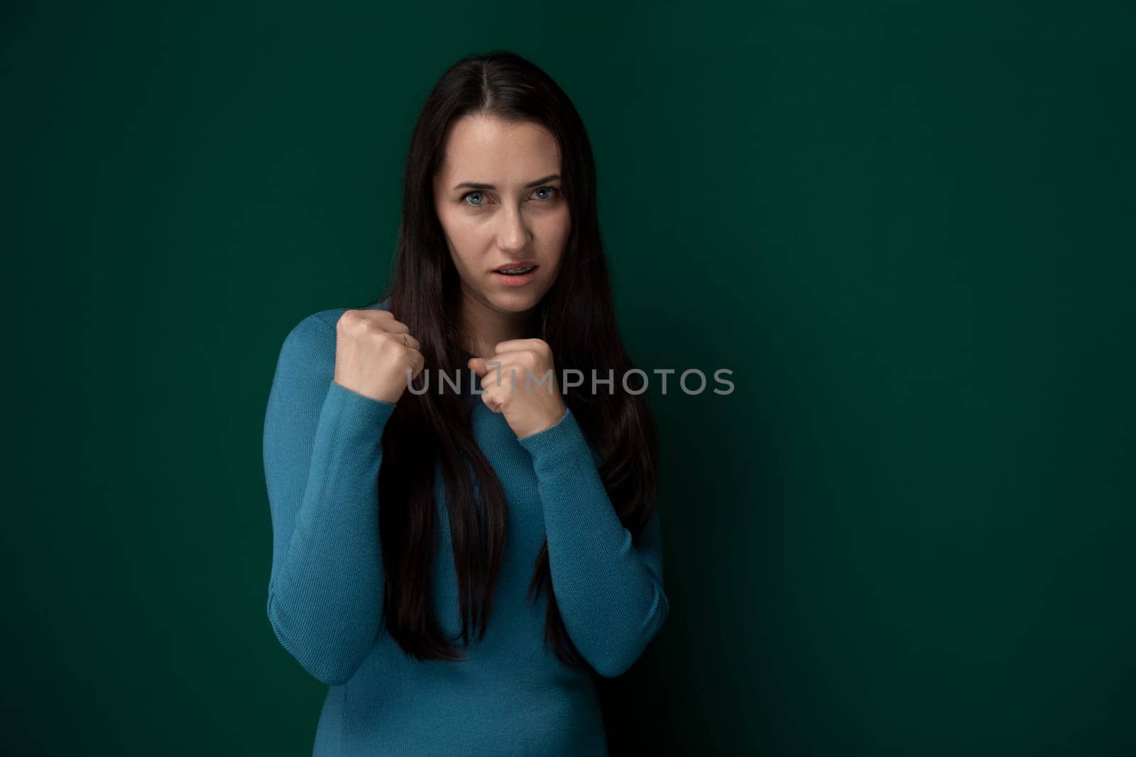 A woman wearing a blue shirt is striking a pose for a photograph. She stands confidently, looking directly at the camera with a slight smile. Her posture is relaxed yet poised, showcasing her outfit and personal style.