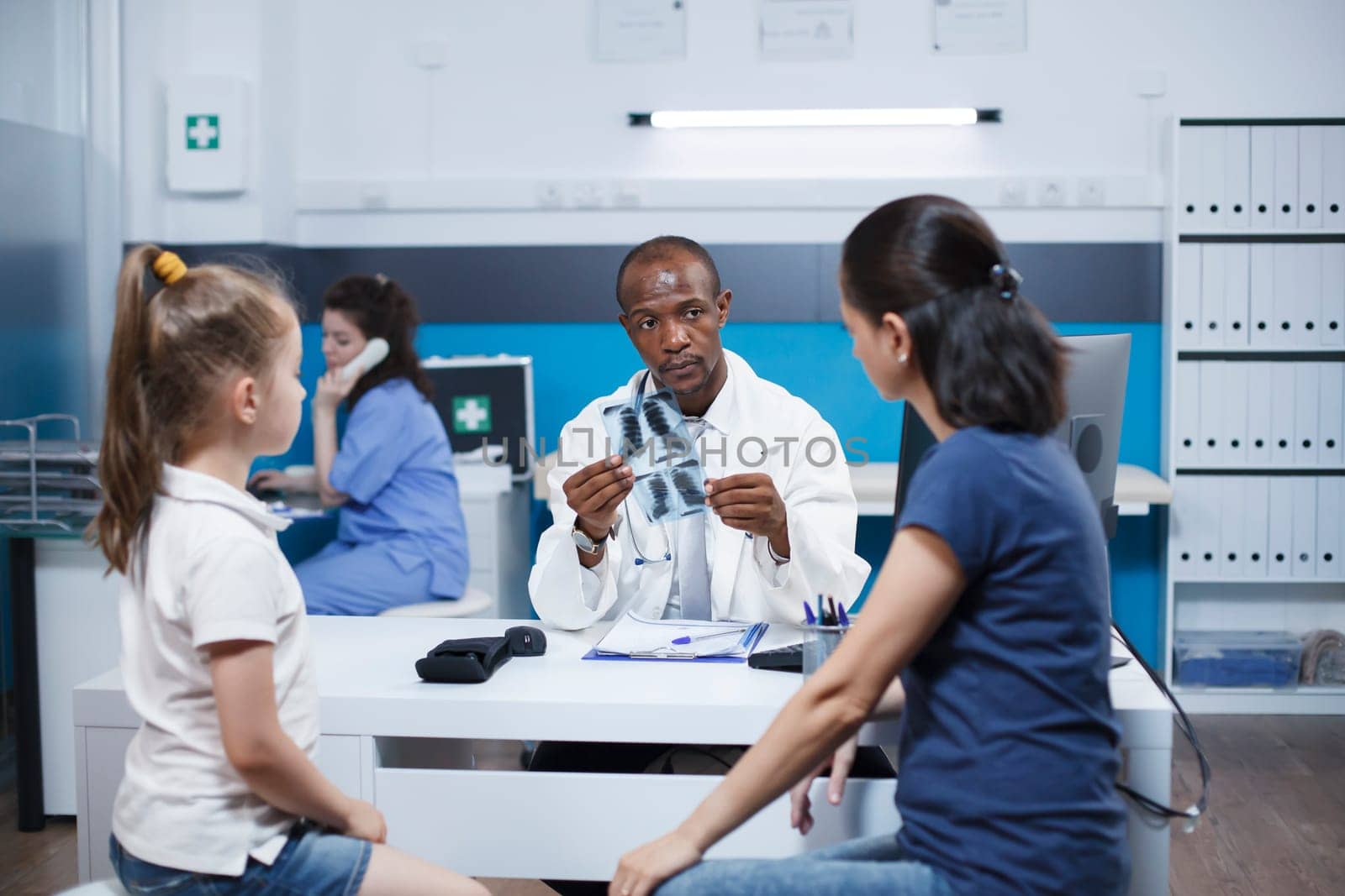 Pediatrician examines chest scan of girl by DCStudio