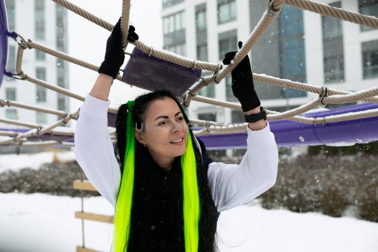 A woman wearing winter clothing is gripping onto a thick rope as she navigates through a snowy landscape. She appears determined and focused on her task.