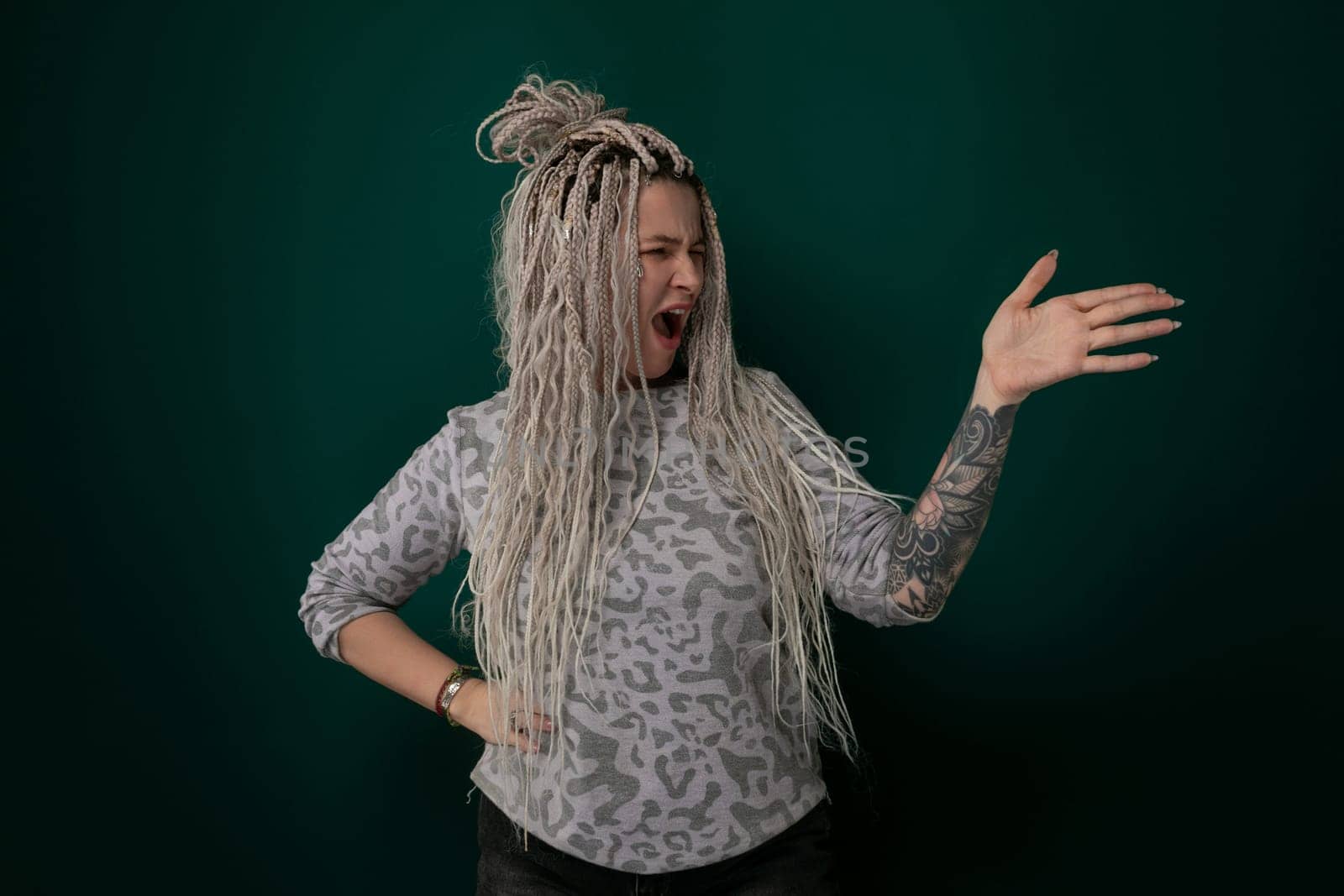 A woman with dreadlocks is contorting her facial expression, possibly showing disgust or amusement. Her distinctive hairstyle frames her face as she gestures, creating a visually striking moment.