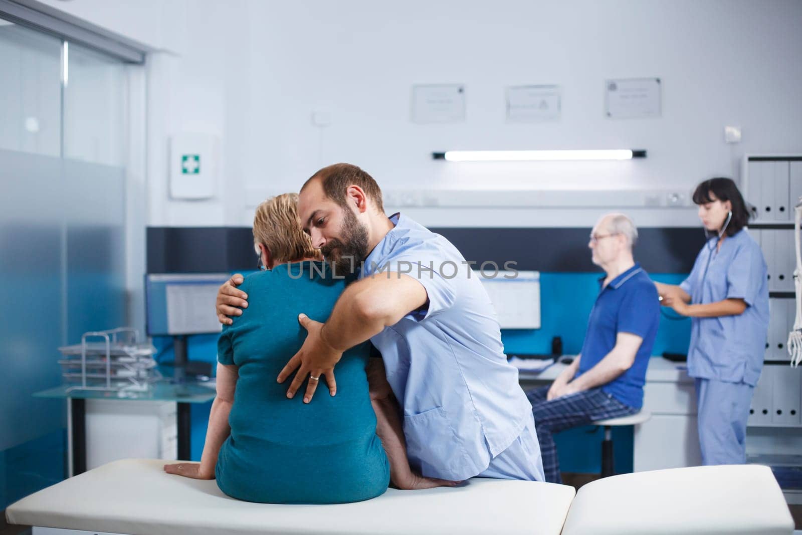 Nurse in blue scrubs treating old woman with back and spine pain for physical recovery. Chiropractic doctor giving assistance to retired patient with spinal cord injury and orthopedic care.