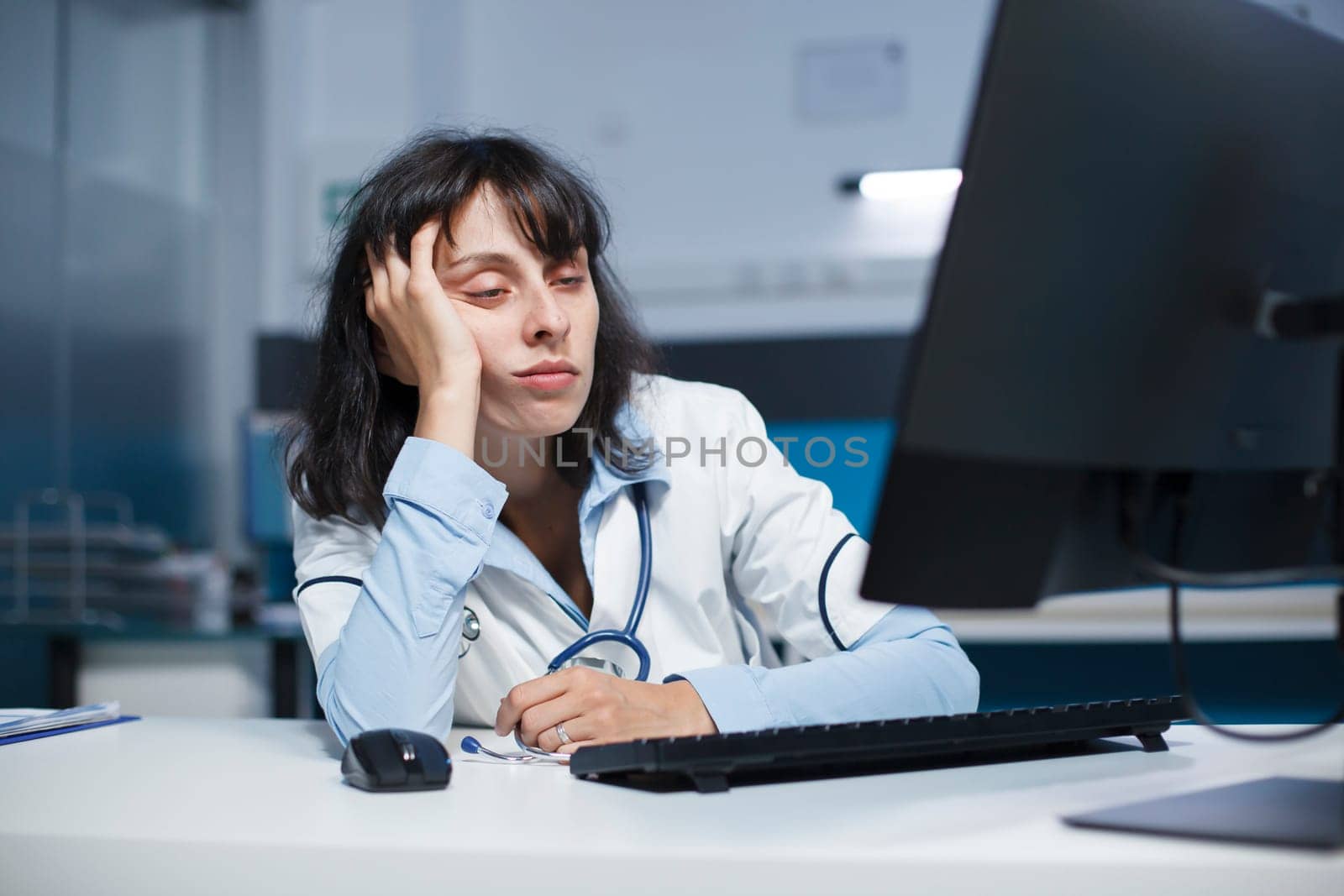 Tired female doctor in hospital office by DCStudio