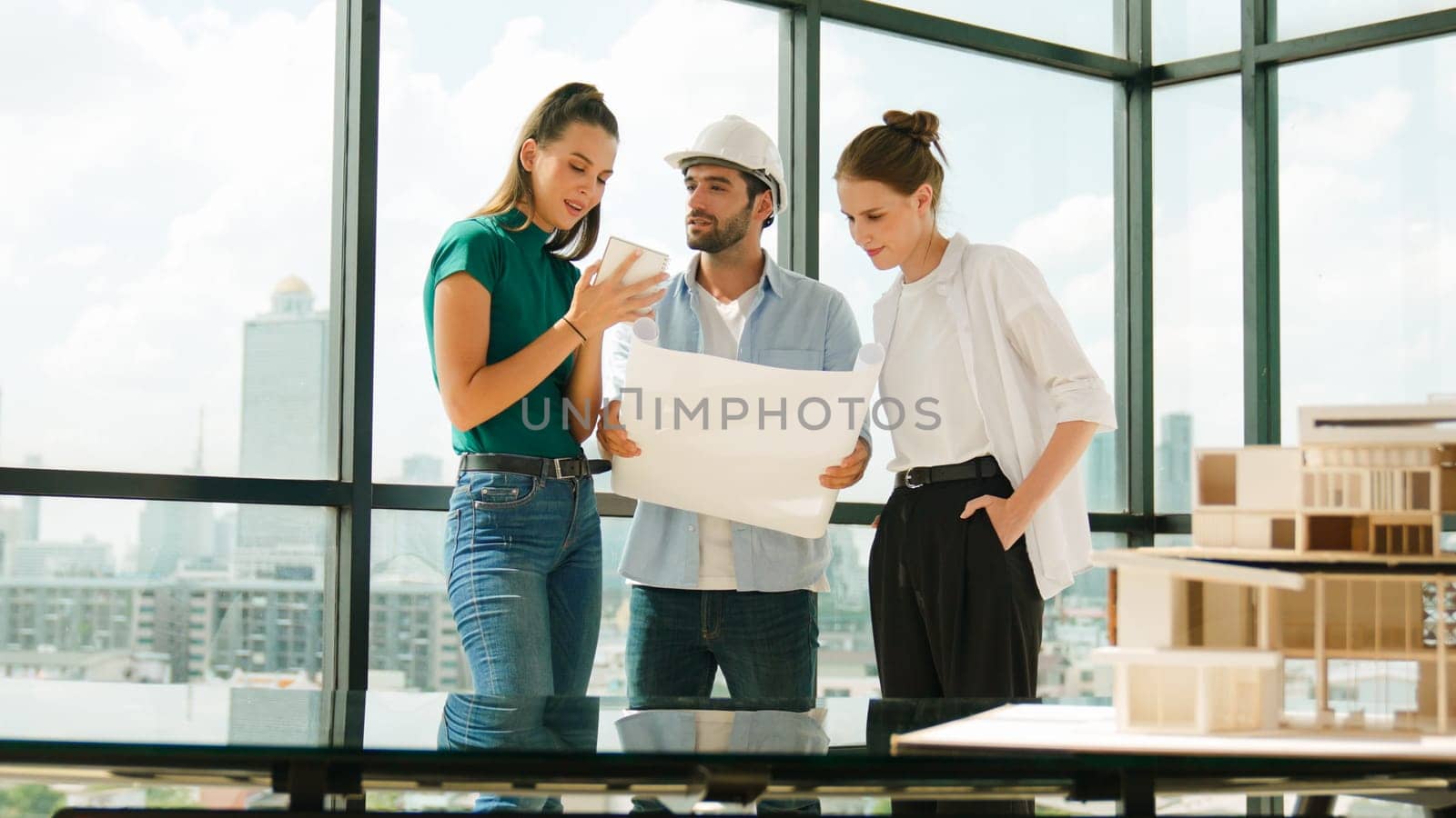 Professional architect engineer team talking, sharing, brainstorming about design while manager hold at project plan. Young architect holding plan while manager listen and point at plan. Tracery