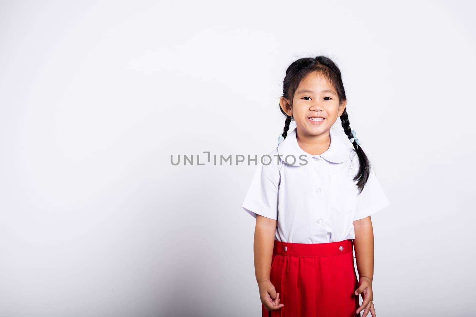 Asian adorable toddler smiling happy wearing student thai uniform red skirt standing in studio shot isolated on white background, Portrait little children girl preschool, Happy child Back to school