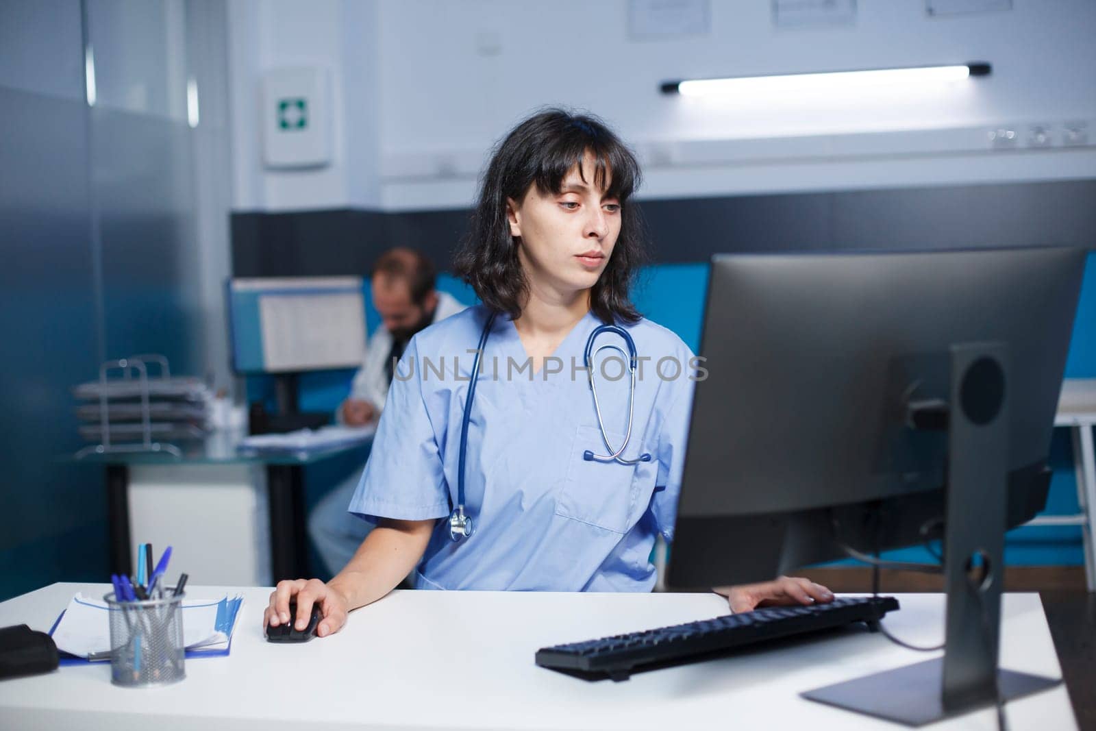 Nurse checking medical files on desktop by DCStudio