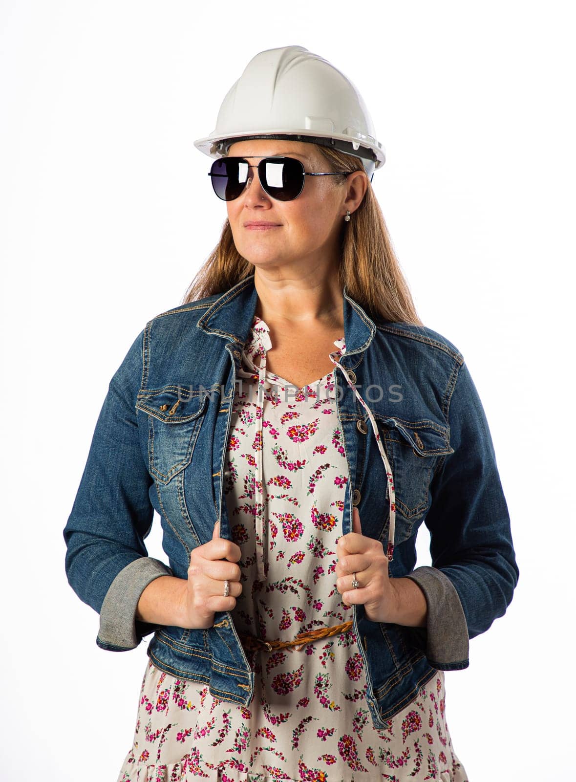 Forty something woman, wearing casual clothes, hard hat and sunglasses, holding her demin jacket