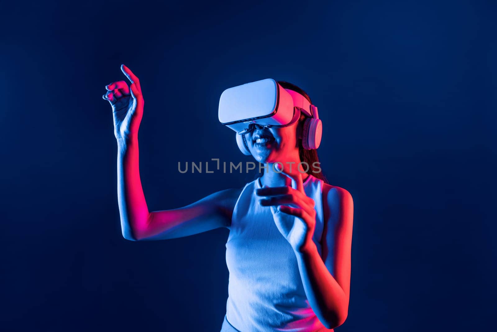 Smart female standing in cyberpunk neon light wear VR headset connecting metaverse, futuristic cyberspace community technology. Elegant woman use finger point generated virtual object. Hallucination.