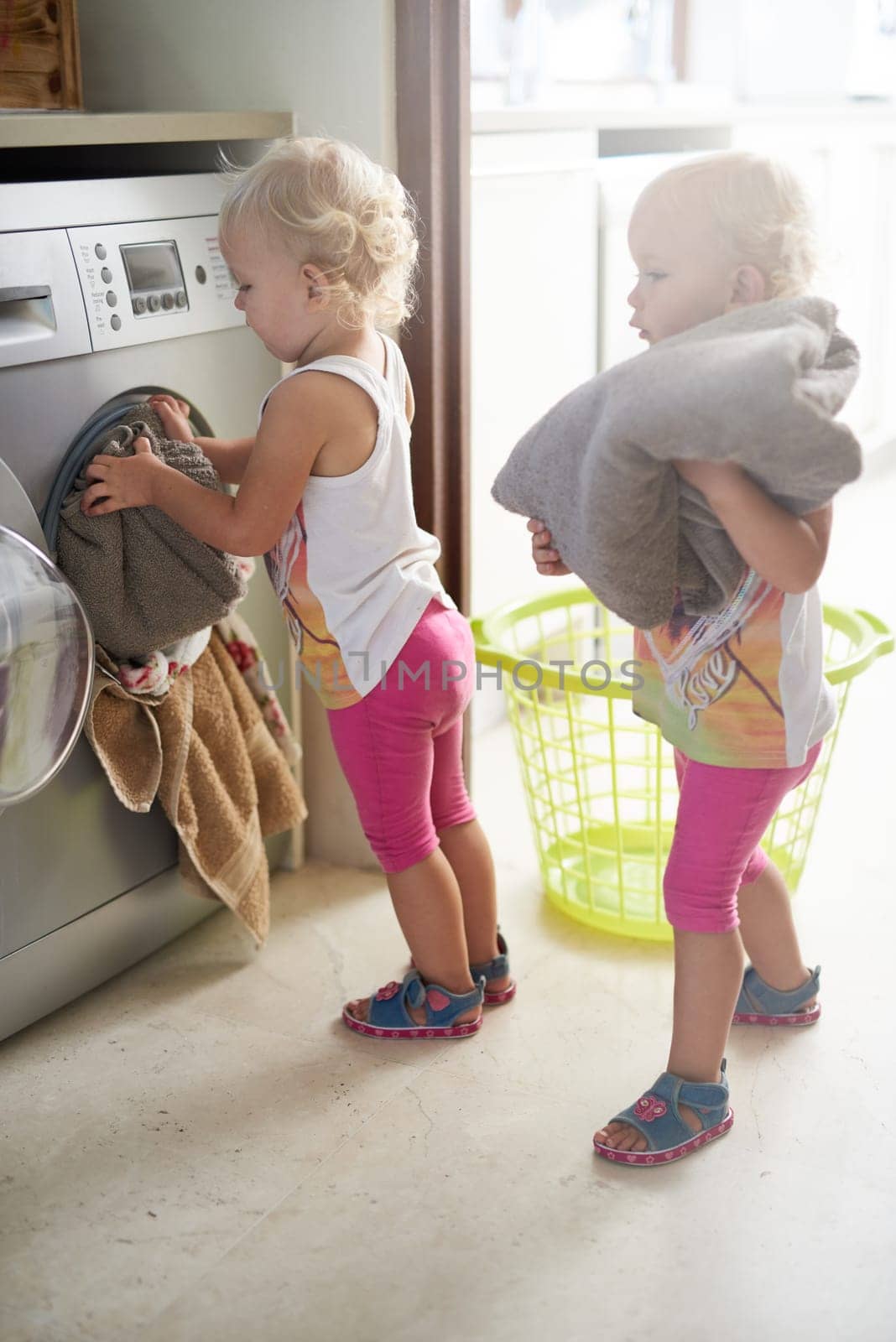 Kids, washing machine and siblings with laundry in house for learning, playing or fun bonding together. Cleaning, games and children help with towels at home for child development, housework or chore.