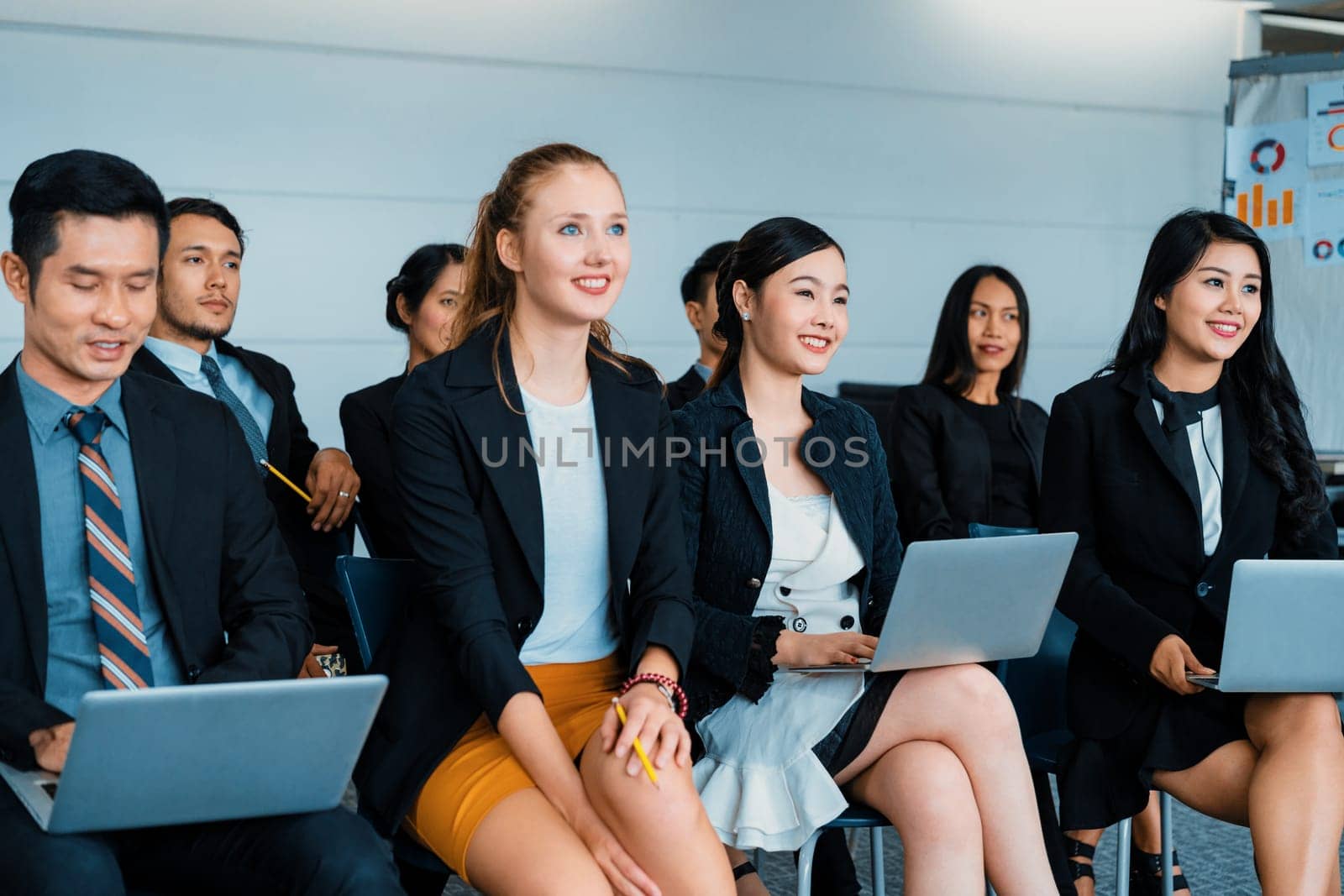 Young Asian and Caucasian audience sitting and listen to speaker in group meeting presentation at office. Businessmen and businesswomen in training workshop. International multicultural business. uds