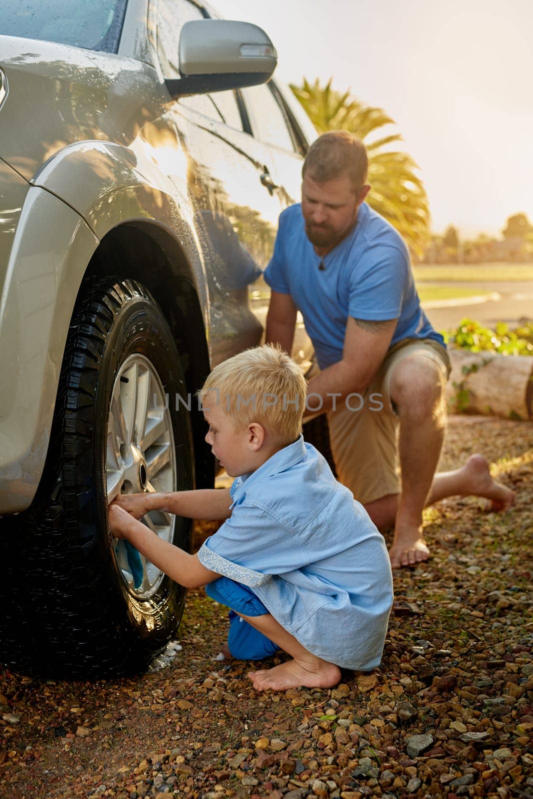 Outdoors, man and child with cleaning car in nature for teamwork, maintenance and childhood development. Dad, boy and kid with washing vehicle on ground for teaching, hygiene and help in parenthood by YuriArcurs