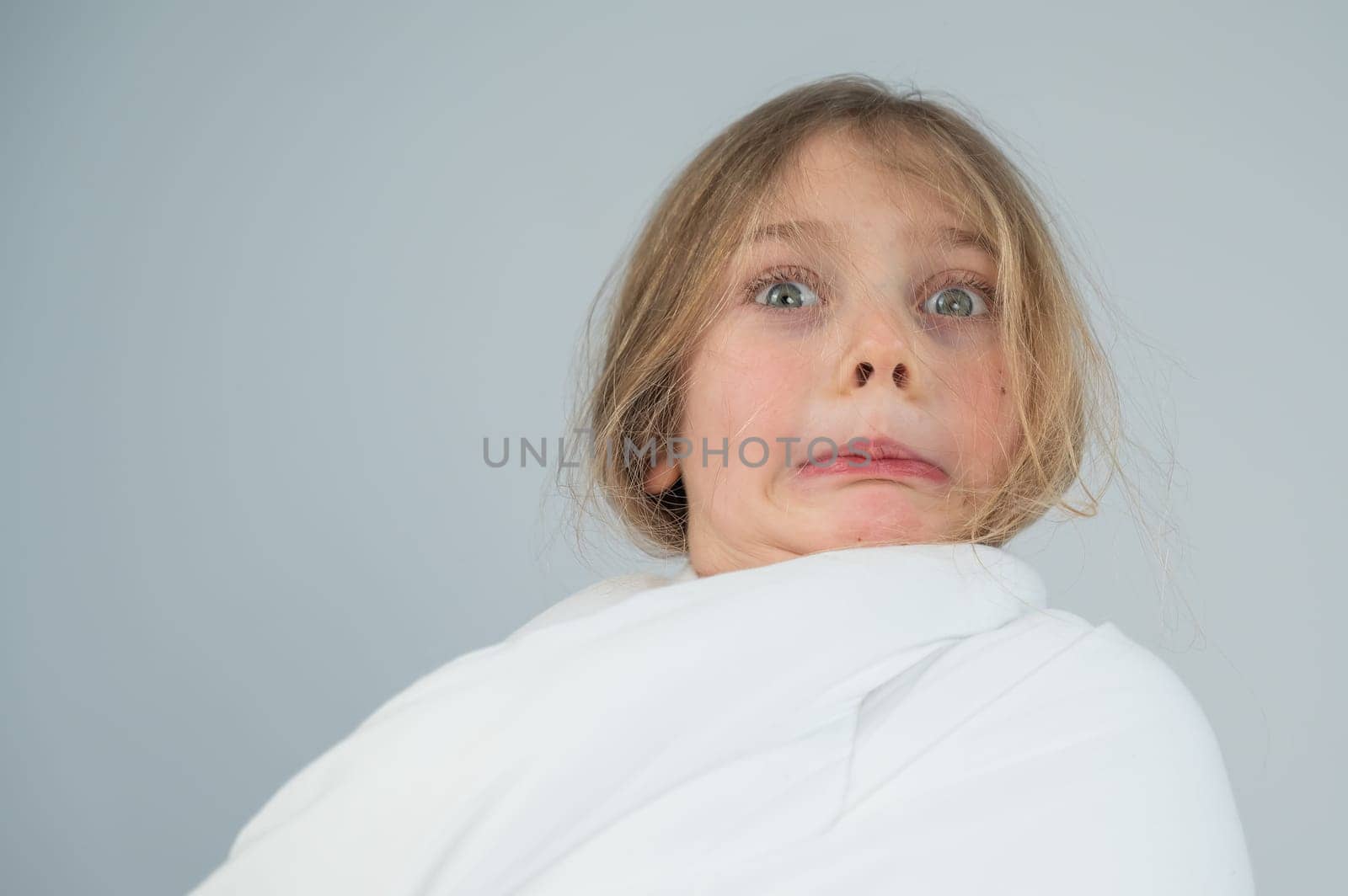 Portrait of a cute little girl wrapped in a white blanket. by mrwed54