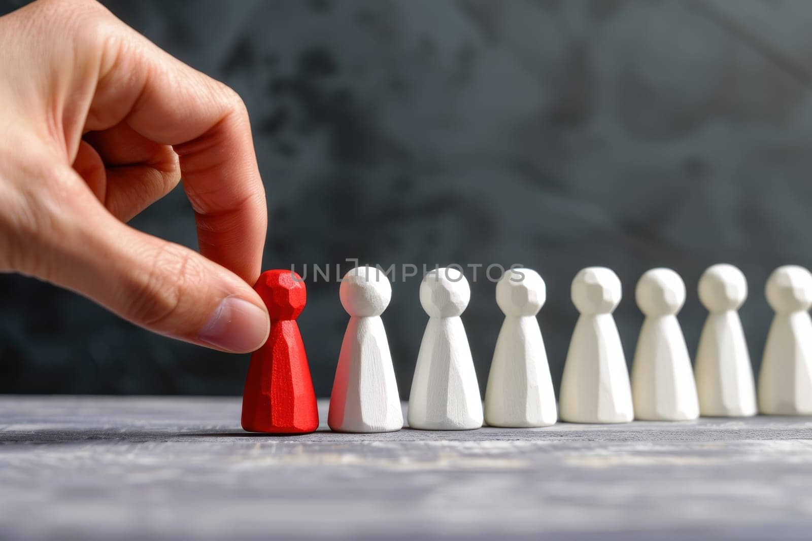 A hand is holding a red piece of wood that is on top of a line of white pieces.