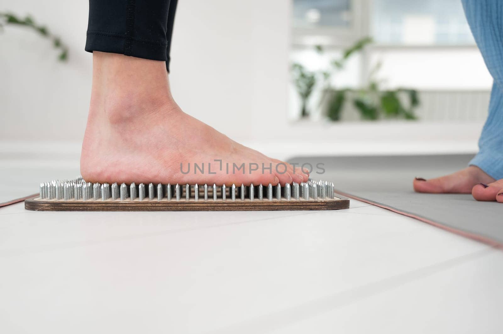 Caucasian woman stands on sadhu boards with therapist support