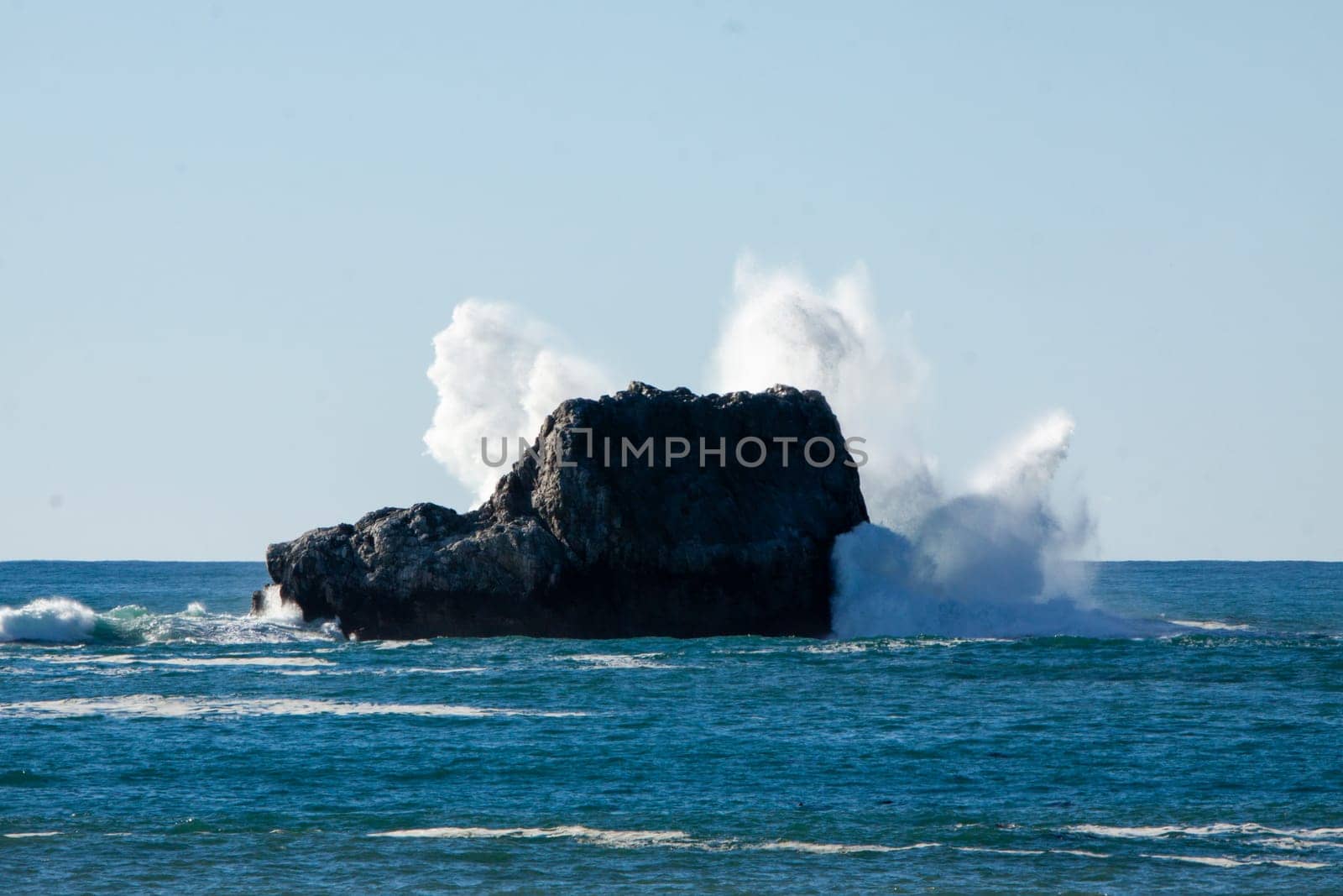 Waves crashing into a rock in central California
