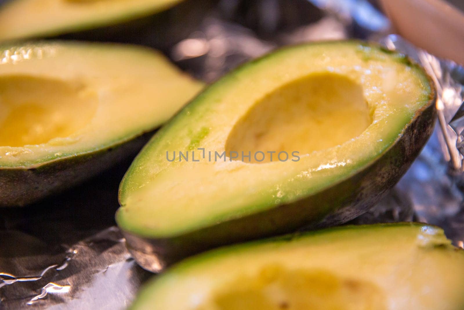 Sliced half of an avocado on aluminum foil