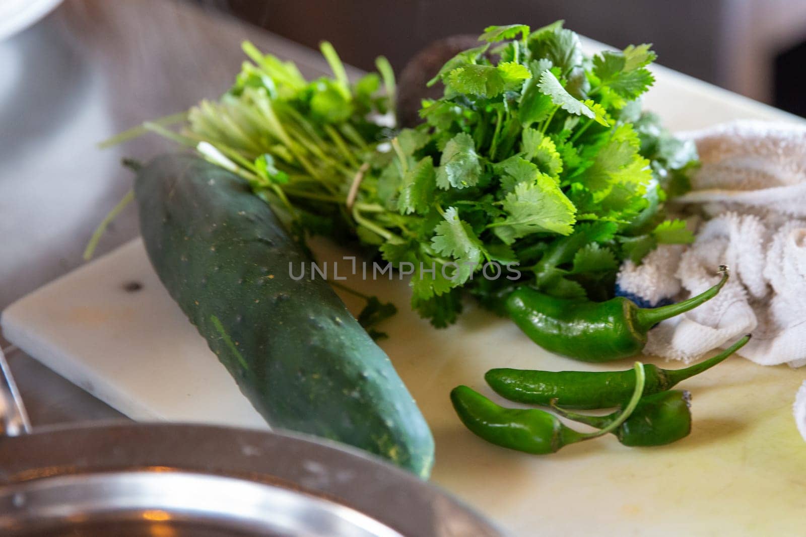 Cucumber, Cilantro, Green Peppers on a cutting board for prep