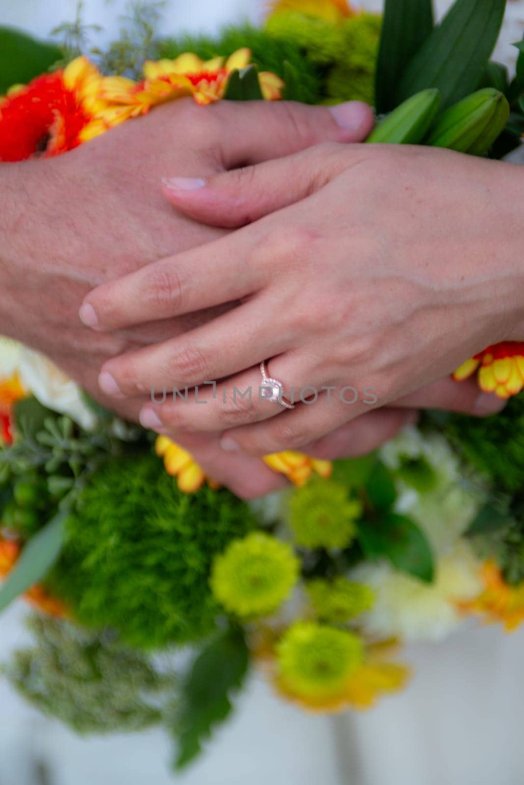 Bride and Groom Hands on Bouquet during a summer wedding